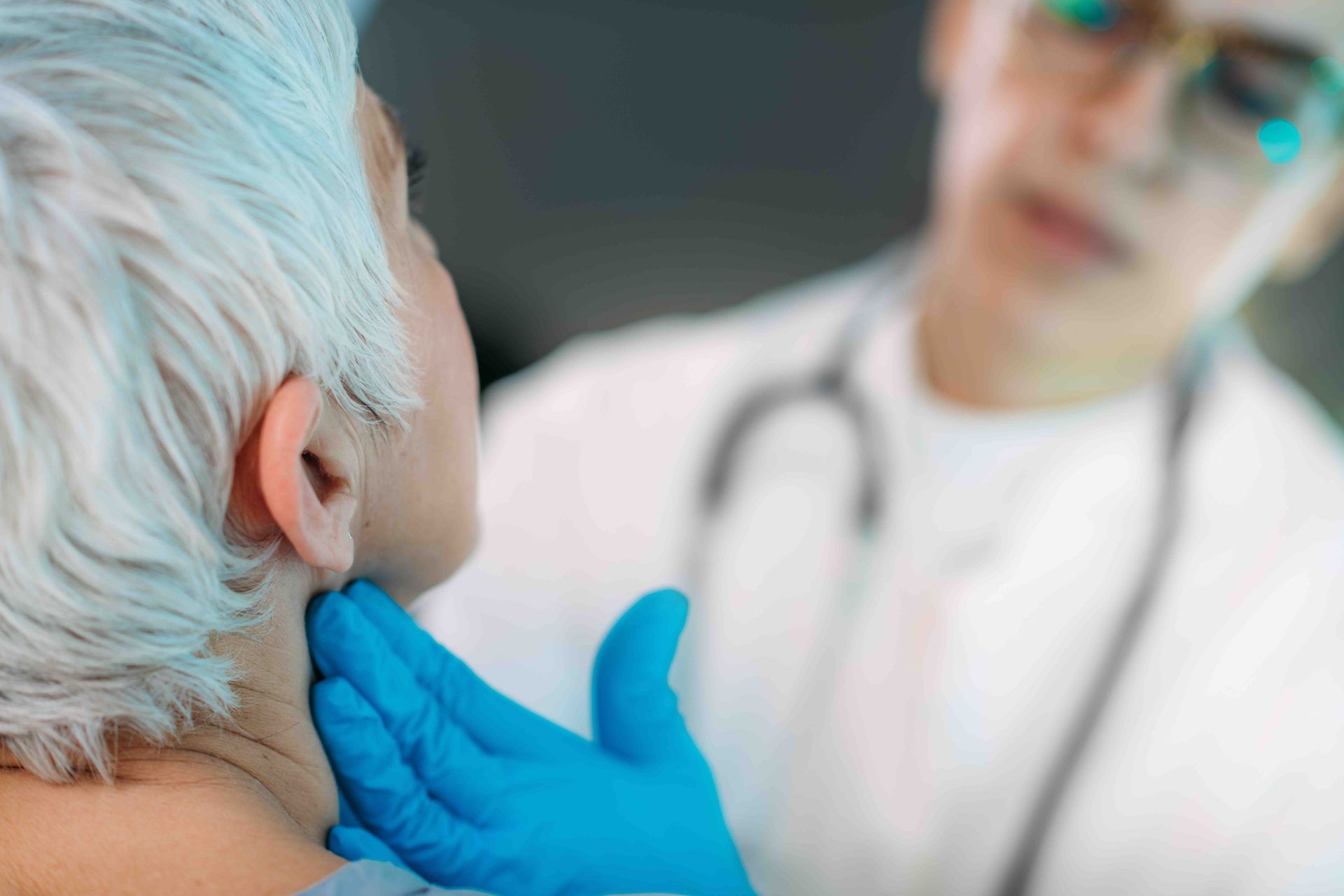 A doctor is examining an older woman's thyroid gland.