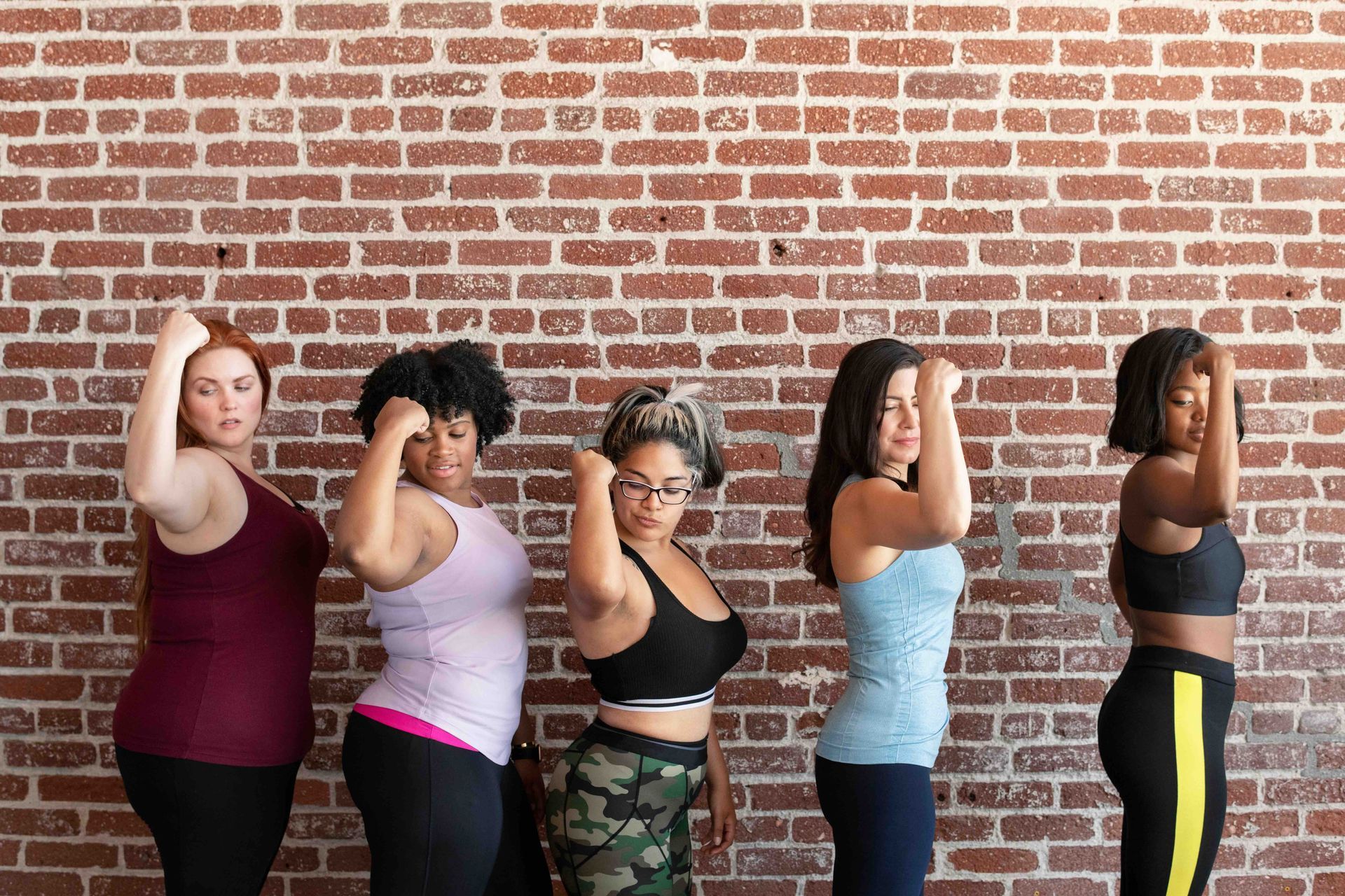 A group of women are standing in front of a brick wall.