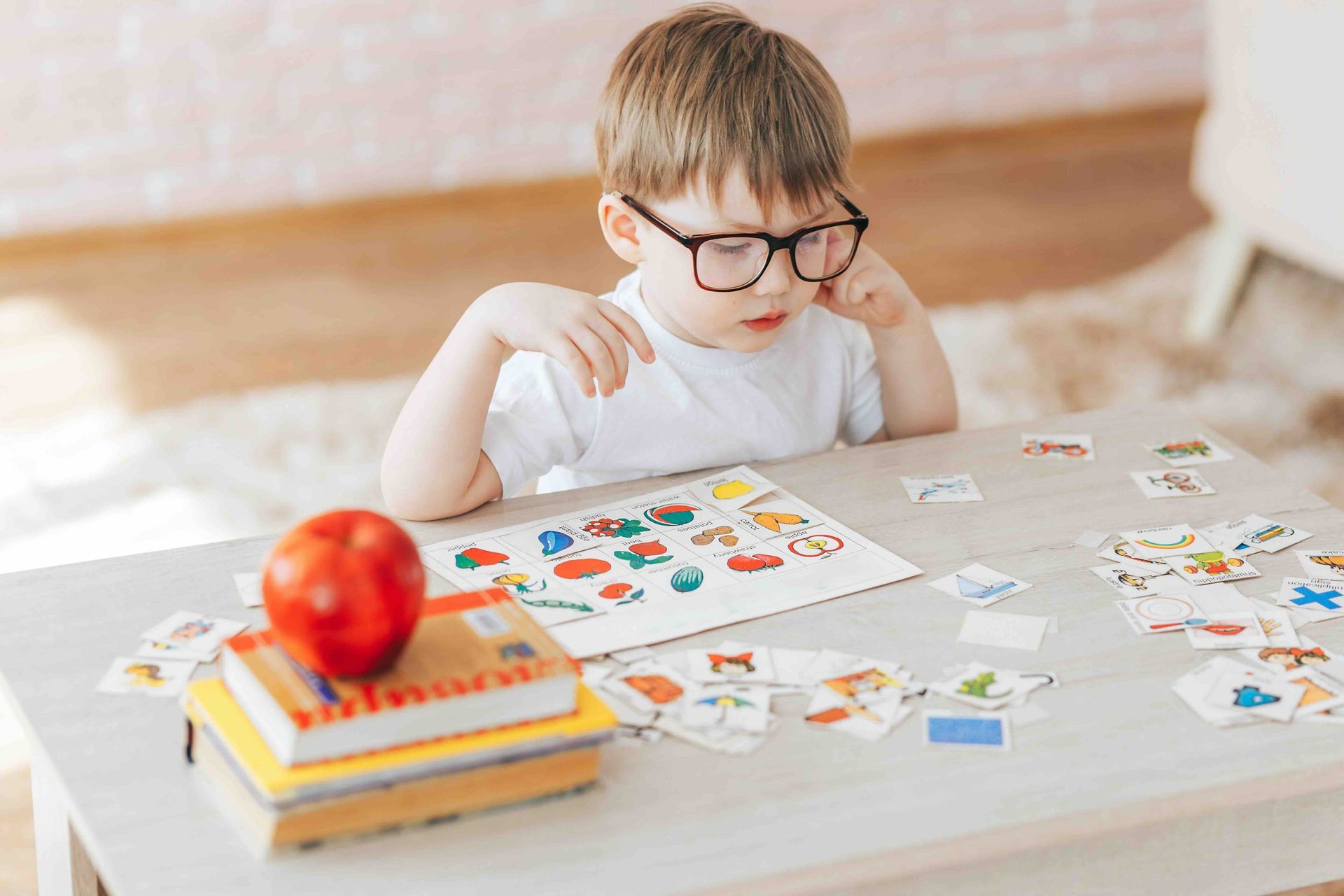 A young boy wearing glasses is sitting at a table playing a game.