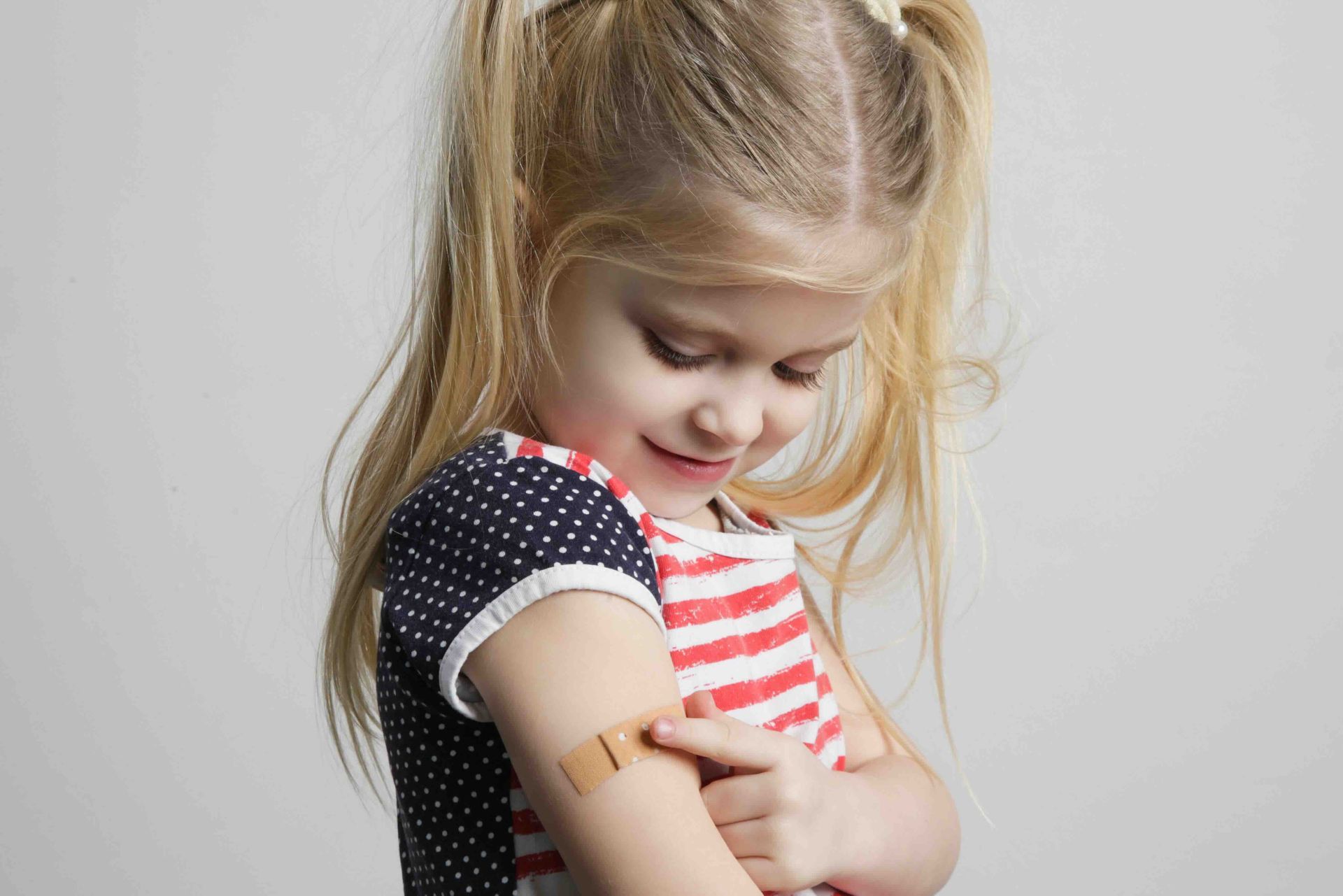 A little girl with a bandage on her arm.