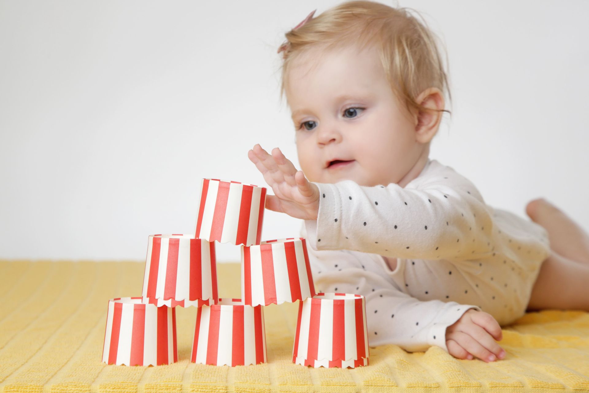 A baby is playing with a stack of red and white striped blocks.