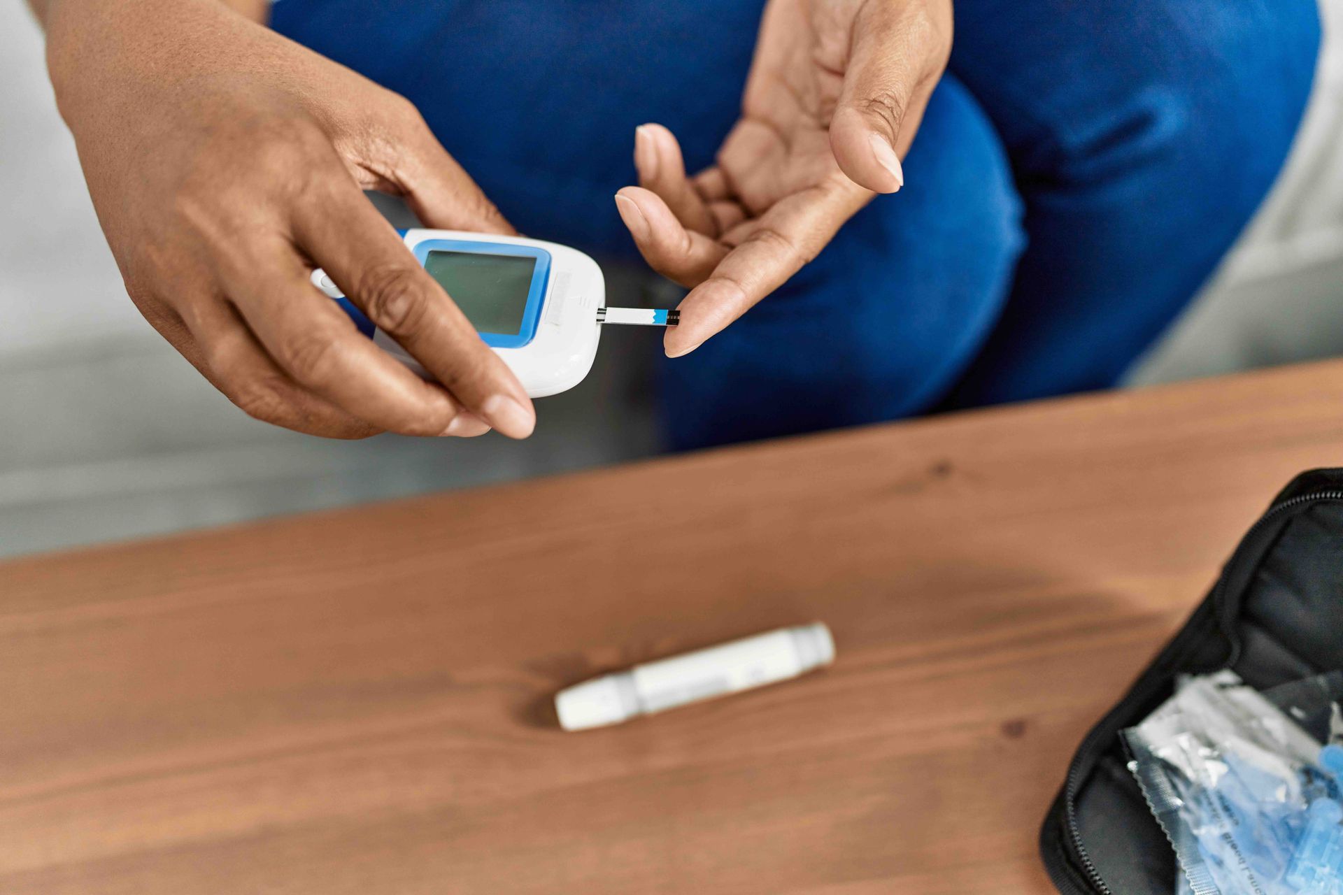 a lady with diabetes is checking her blood sugar by using a glucose monitor and finger poker.