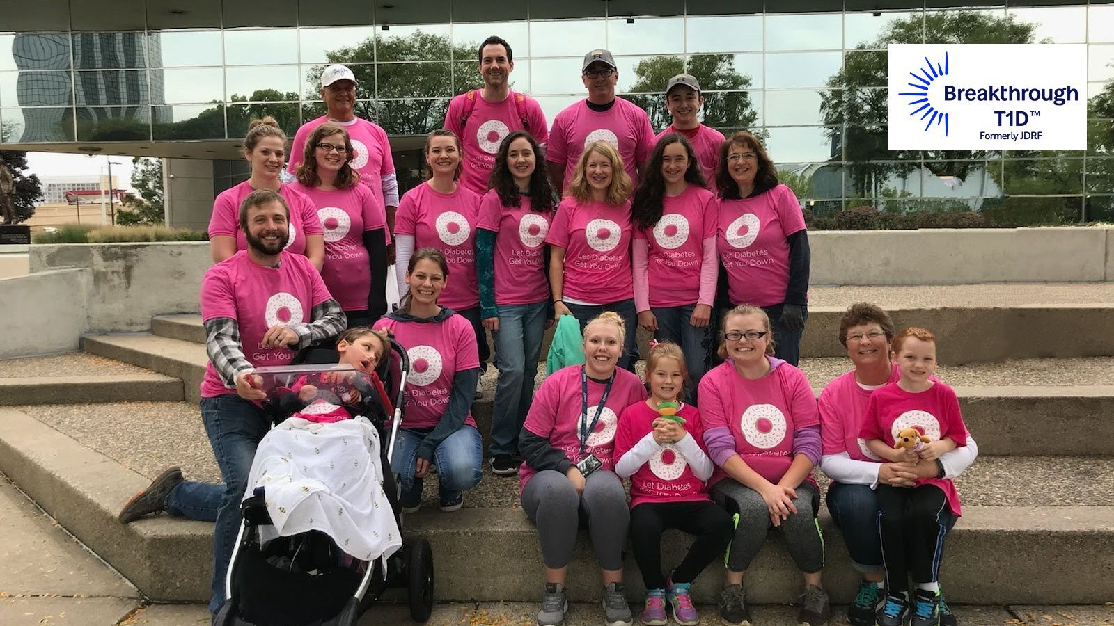 A group of people wearing pink shirts are posing for a picture at a diabetic walk in Grand Rapids, MI.