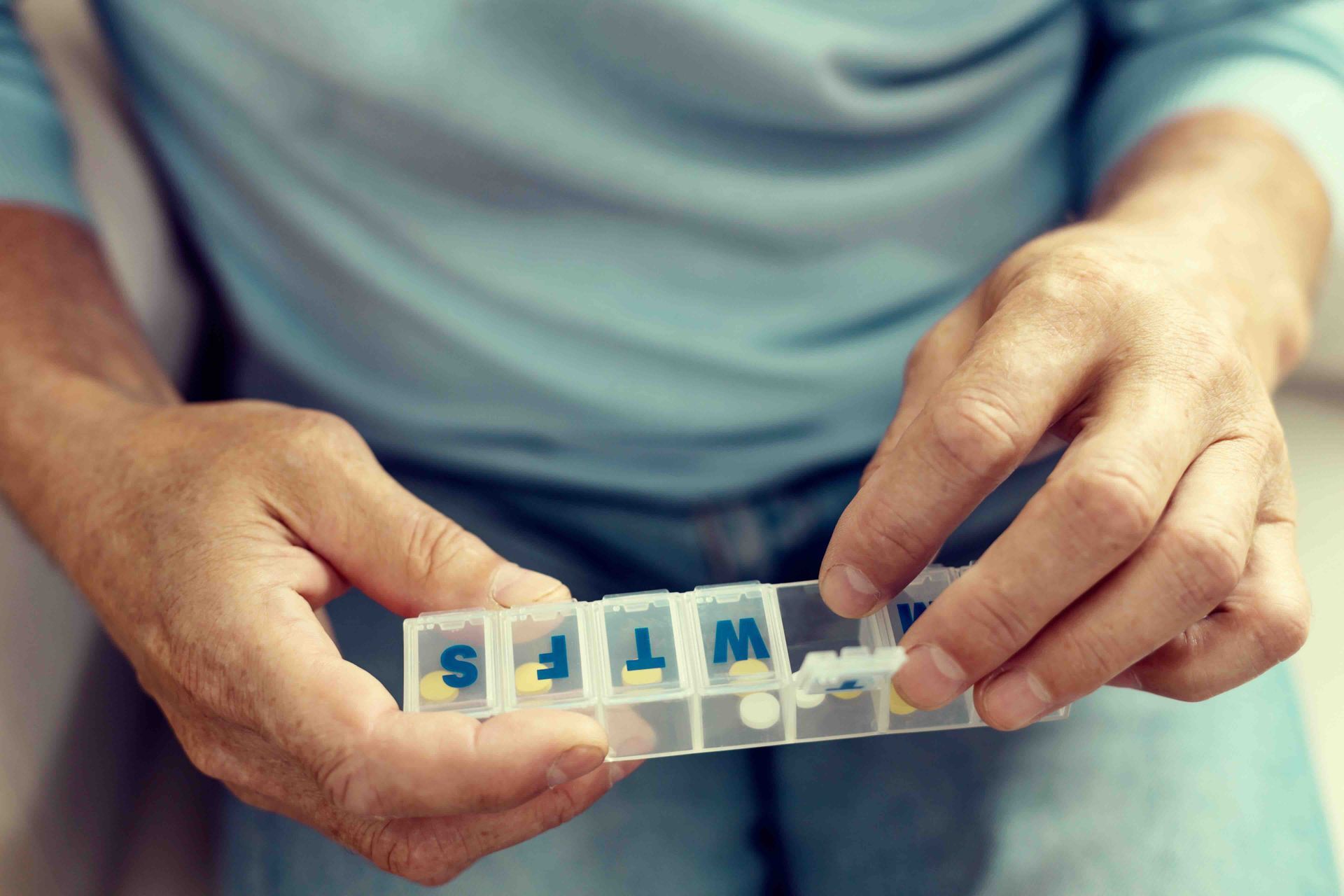 A man is holding a weekly pill organizer in his hands.