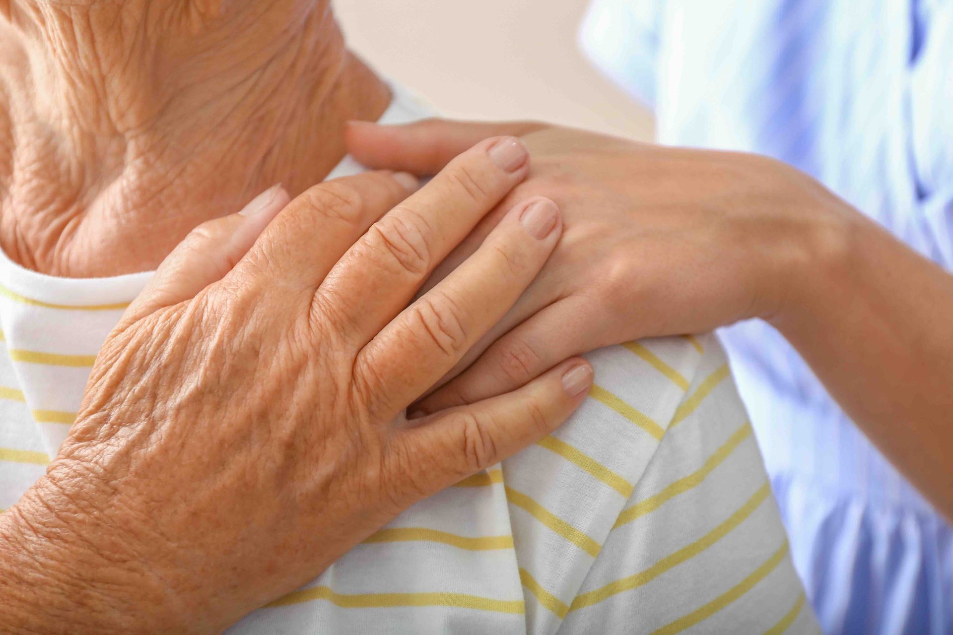 A woman is putting her hand on an older woman 's shoulder.