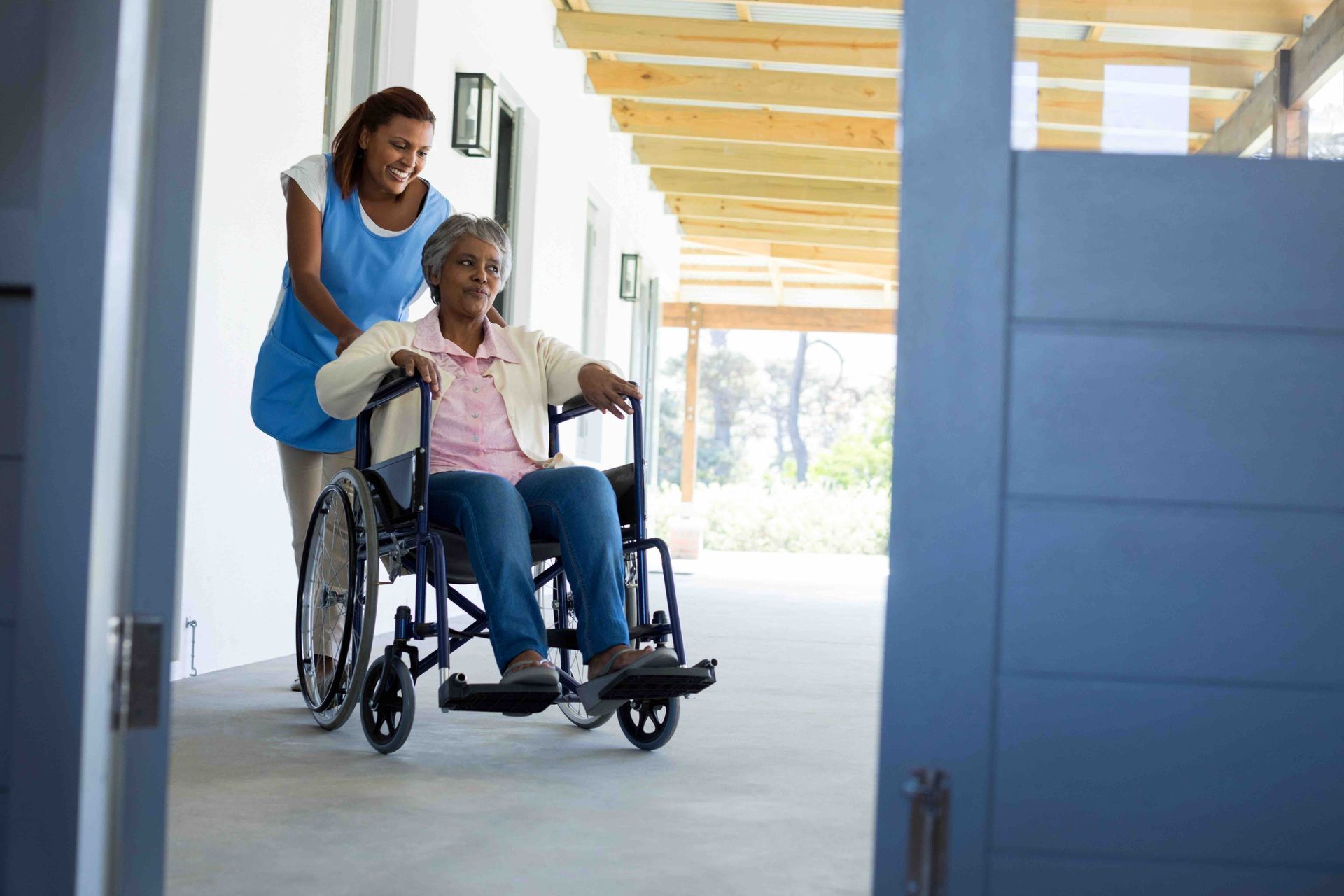 a lady pushing an elderly woman in a wheel chair