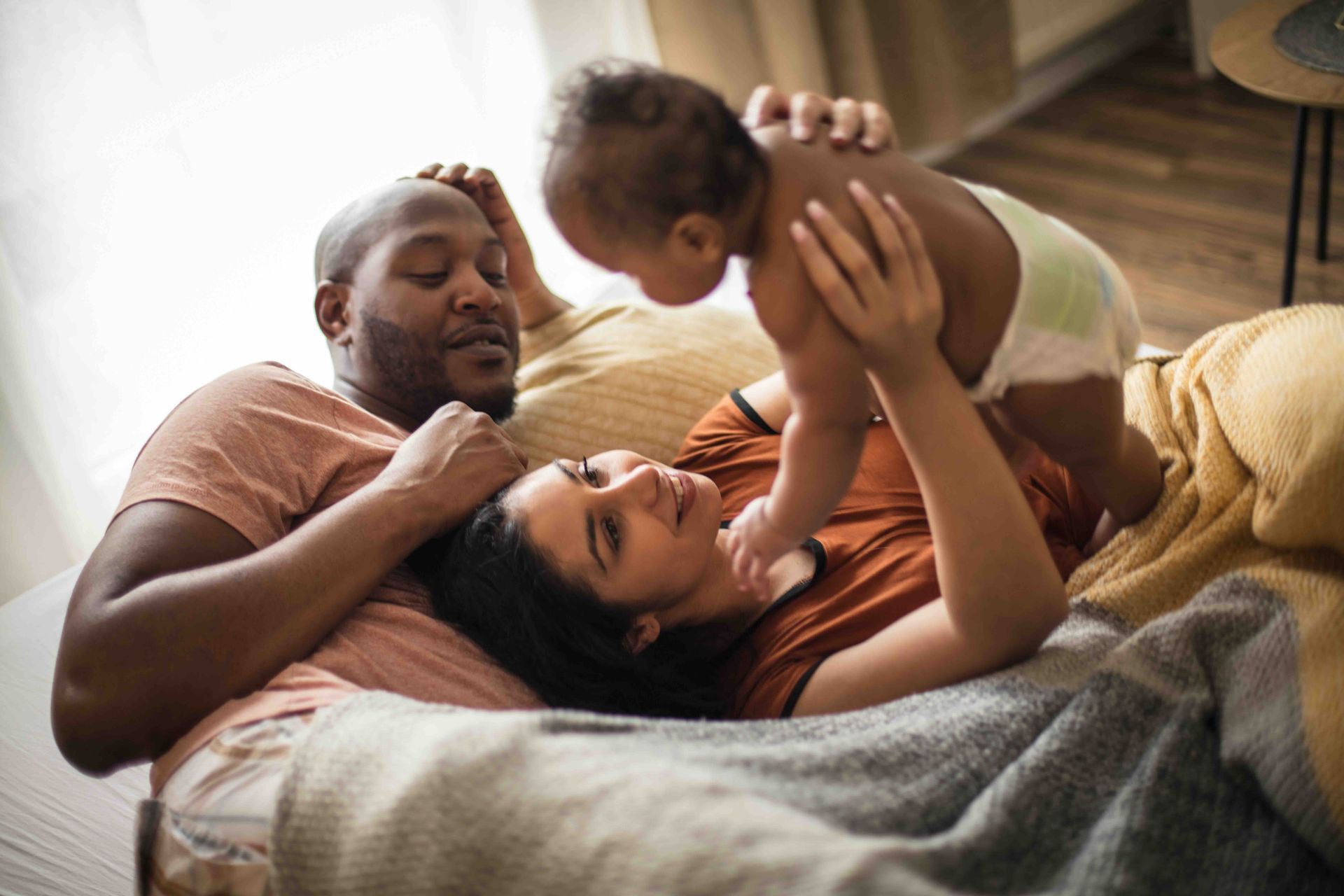 A man and a woman are lying on a couch with a baby.