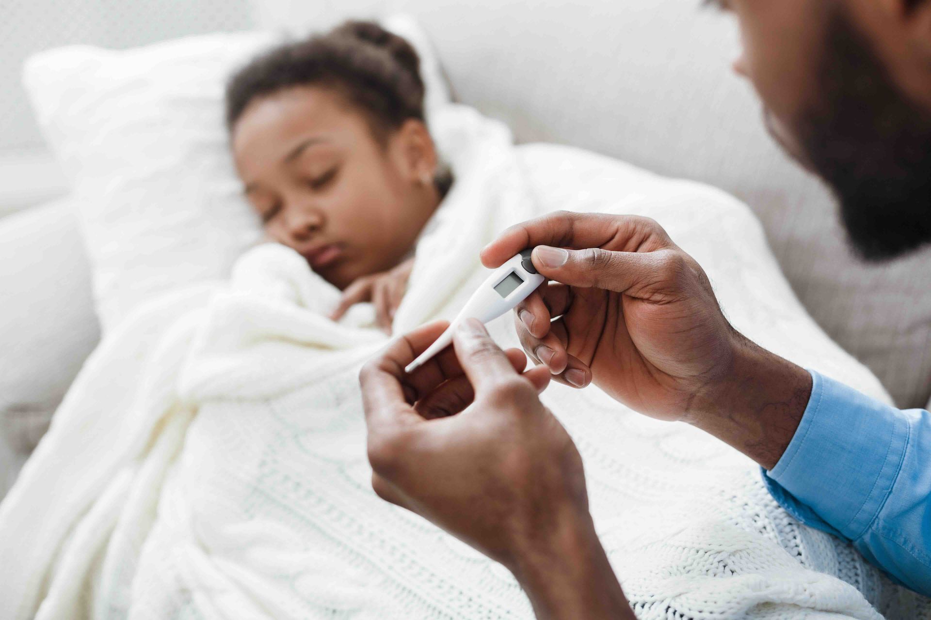 A man is taking a child's temperature with a thermometer.