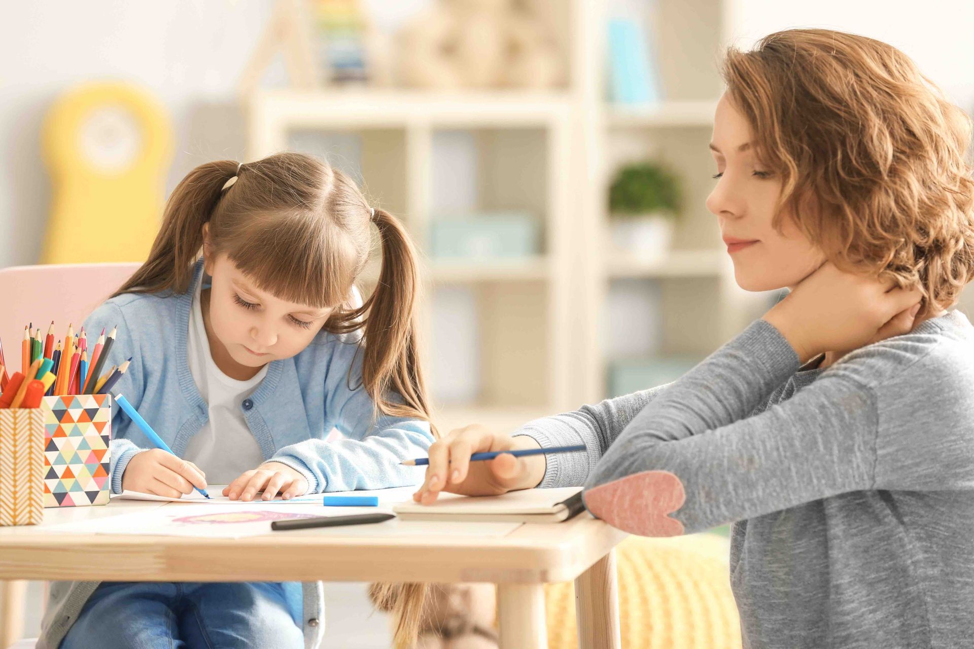 female child coloring with supervisor taking notes