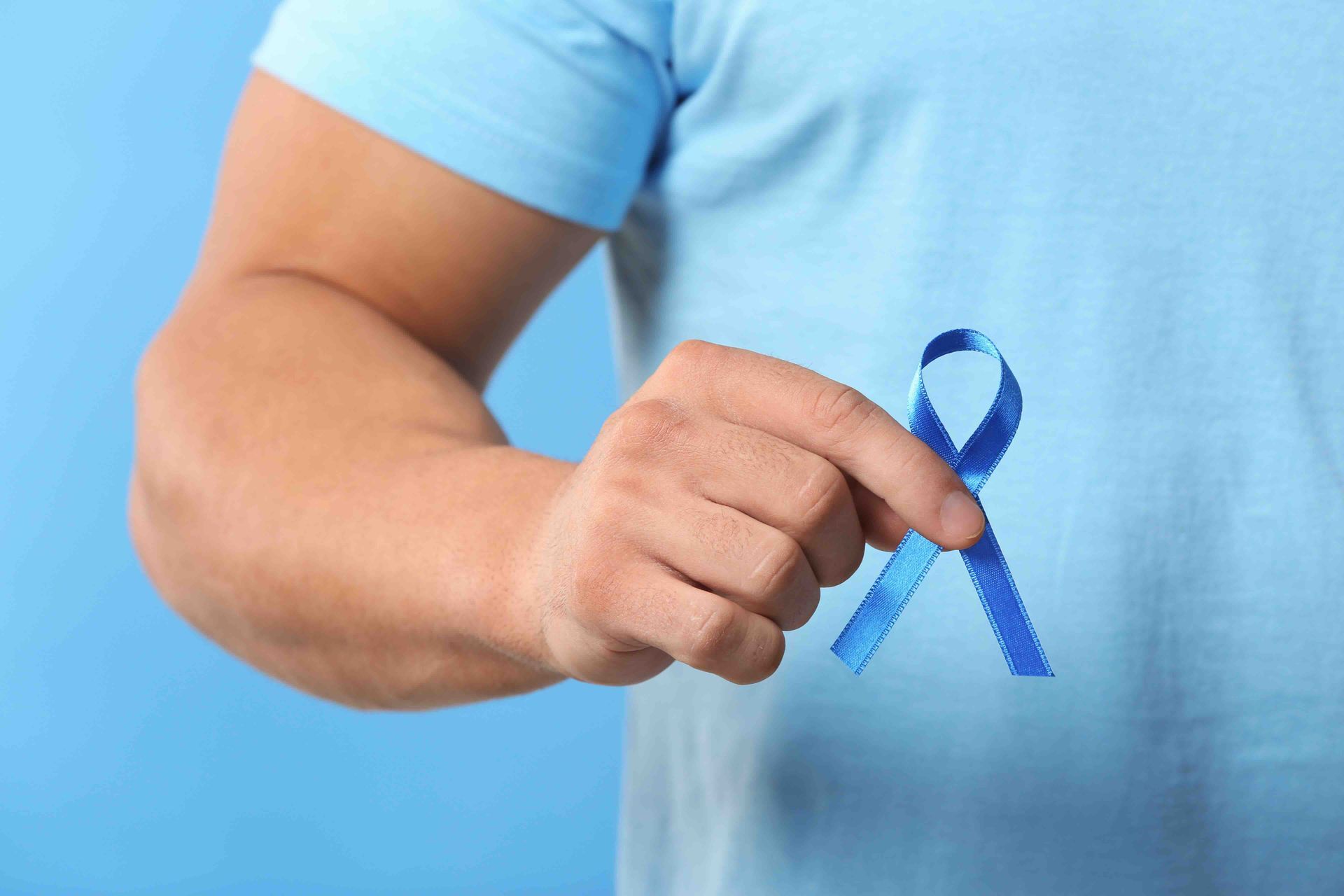 A man is holding a blue ribbon in his hand.