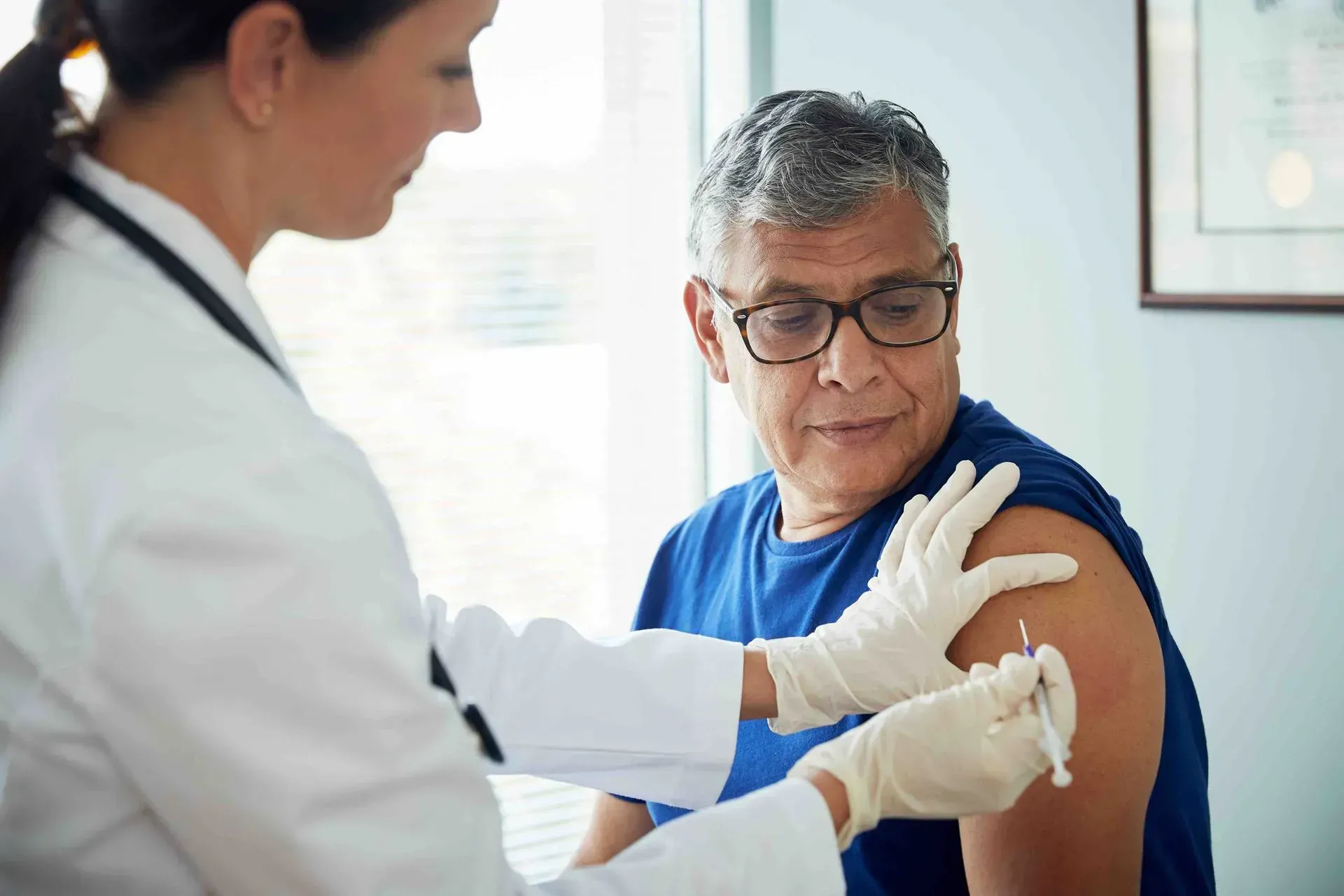 A doctor is giving an older man an injection in his arm.