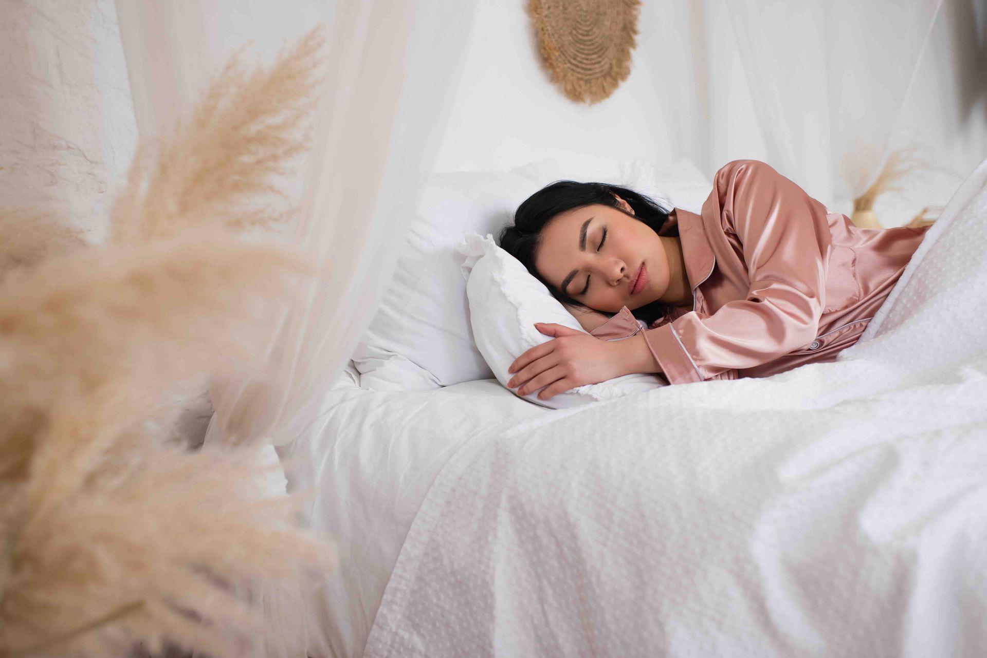 A woman is sleeping on a bed with white sheets and pillows.