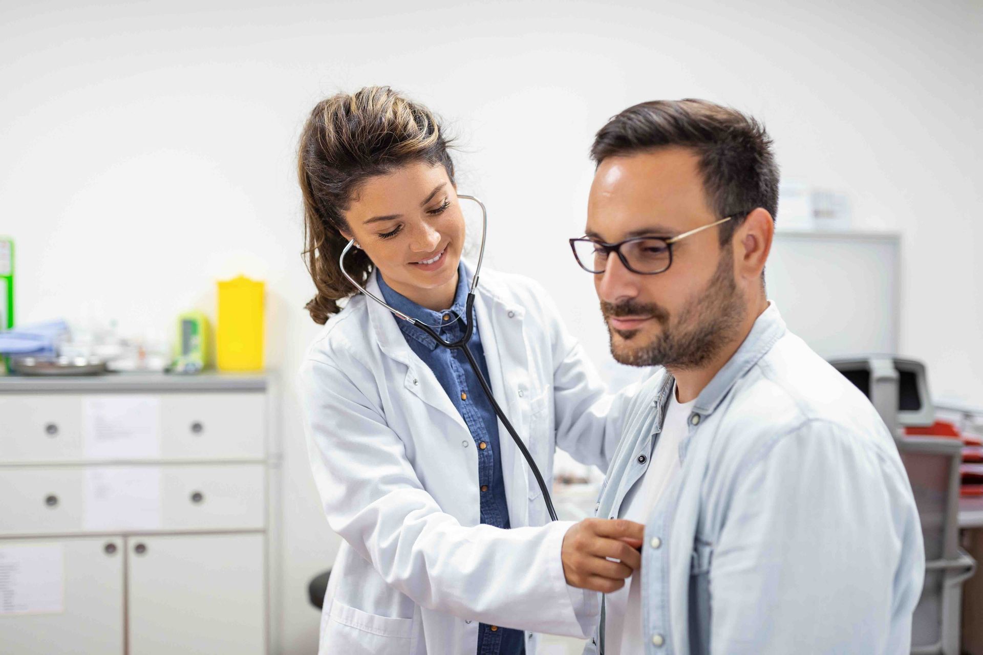 A doctor is listening to a patient 's heart with a stethoscope.