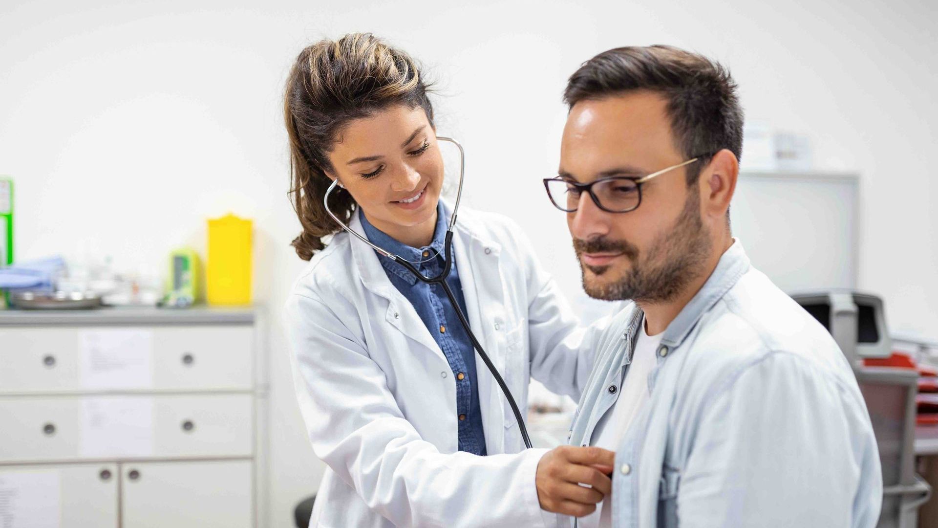 A doctor is listening to a patient's heart with a stethoscope.