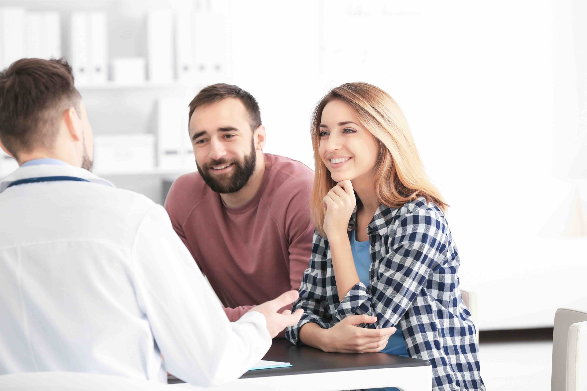A man and a woman are sitting at a table talking to a doctor.