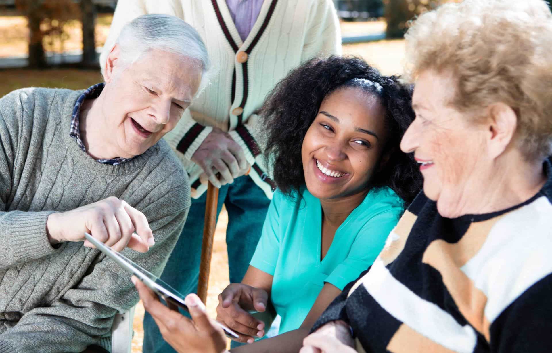 A group of elderly people are looking at a tablet together.