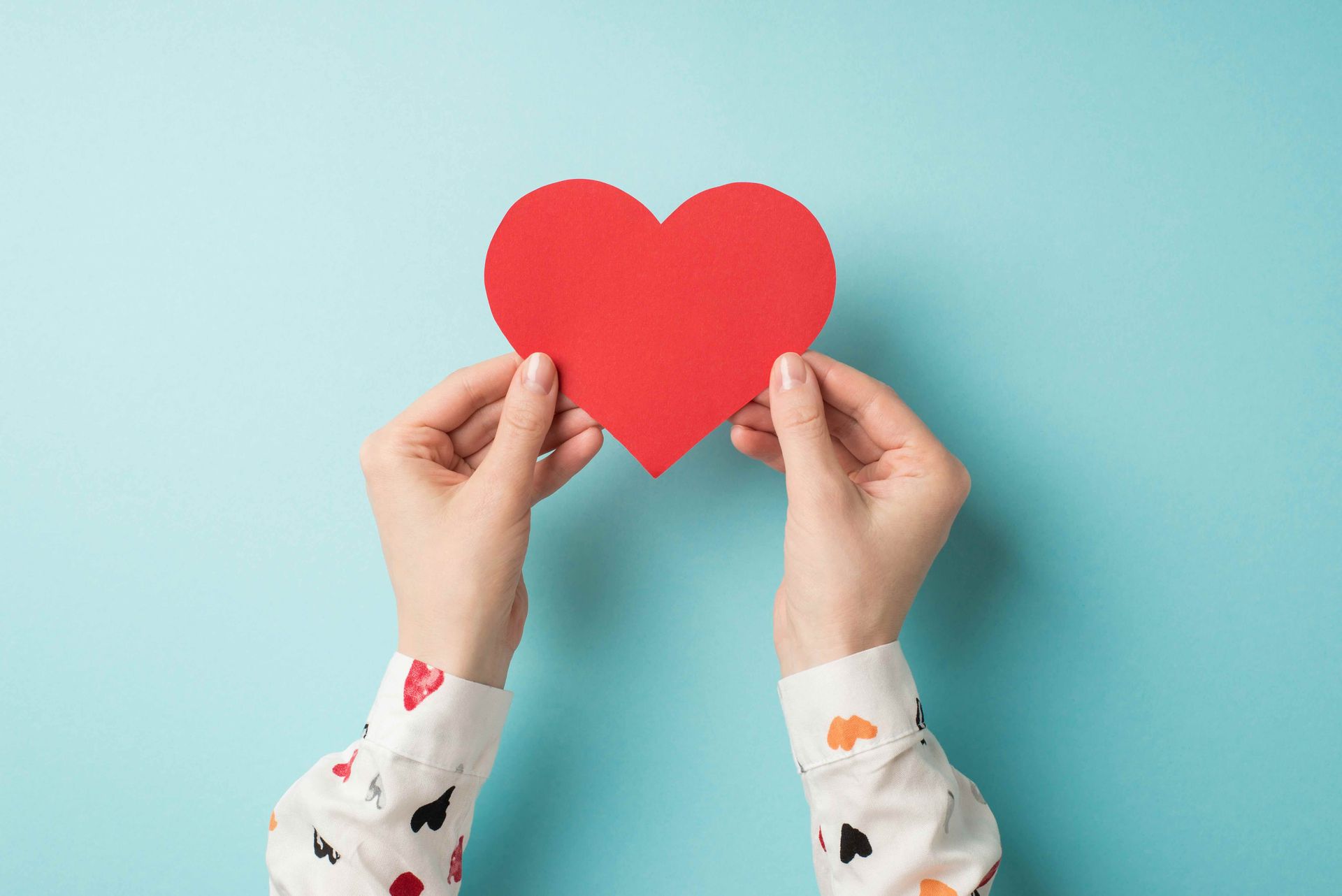 A woman is holding a red heart in her hands on a blue background.