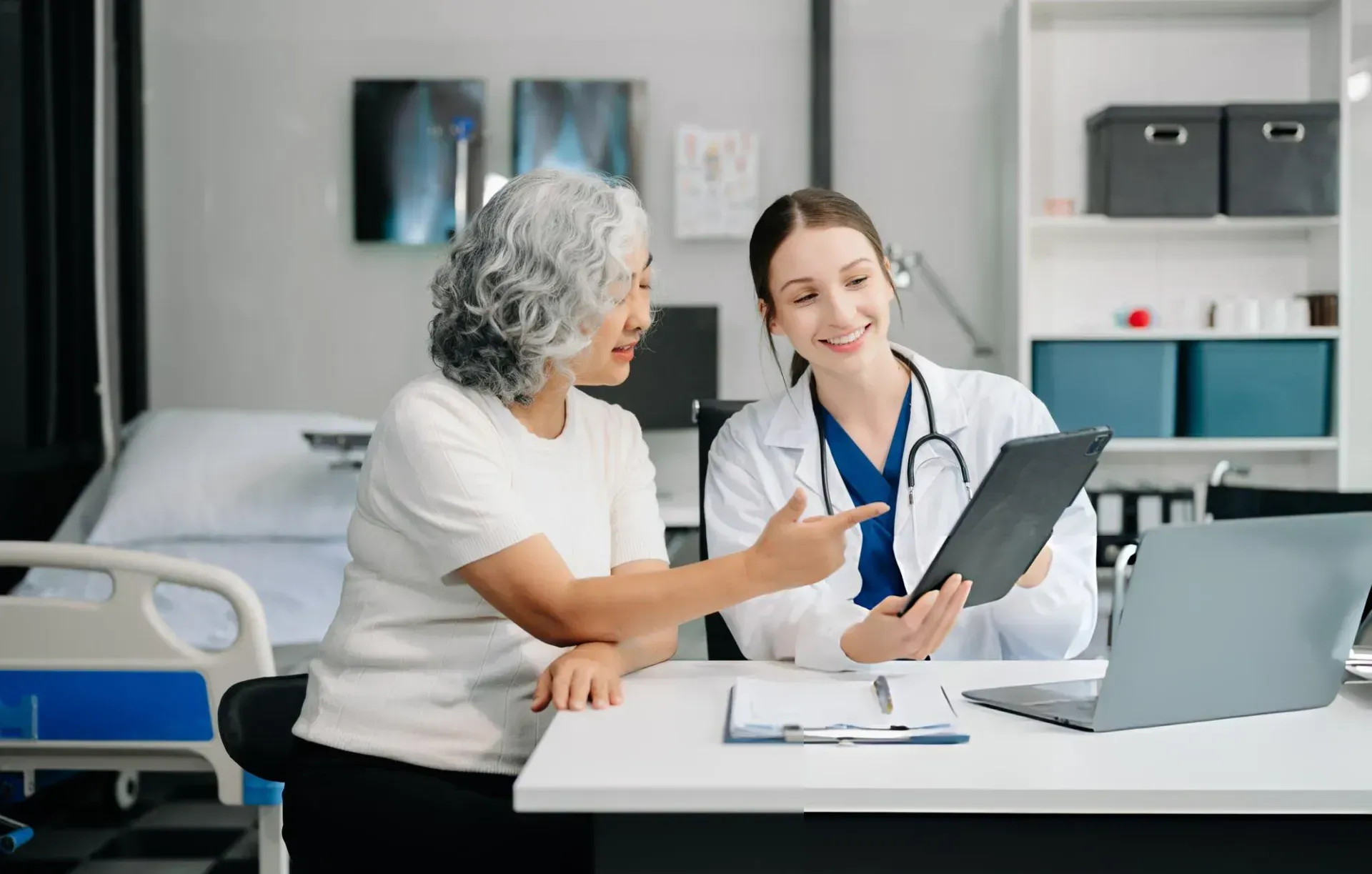 A doctor is talking to an elderly woman while looking at an x-ray.