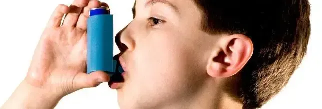 A young boy is using an inhaler to treat his asthma.