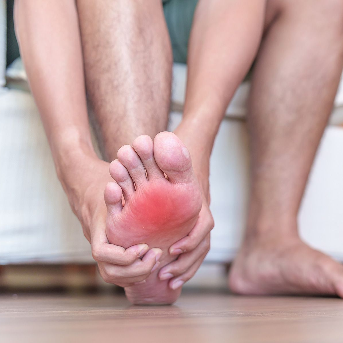 Person holding foot with red highlight indicating pain.