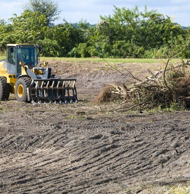 A Yellow Tractor is Driving Through a Dirt Field — Lantry Earthmoving in Phoenix Park, NSW