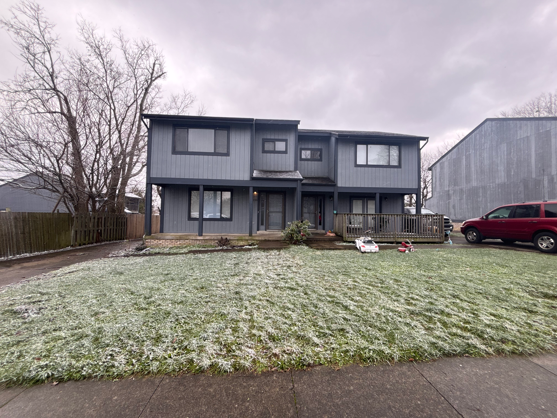 A large gray house with a red truck parked in front of it.