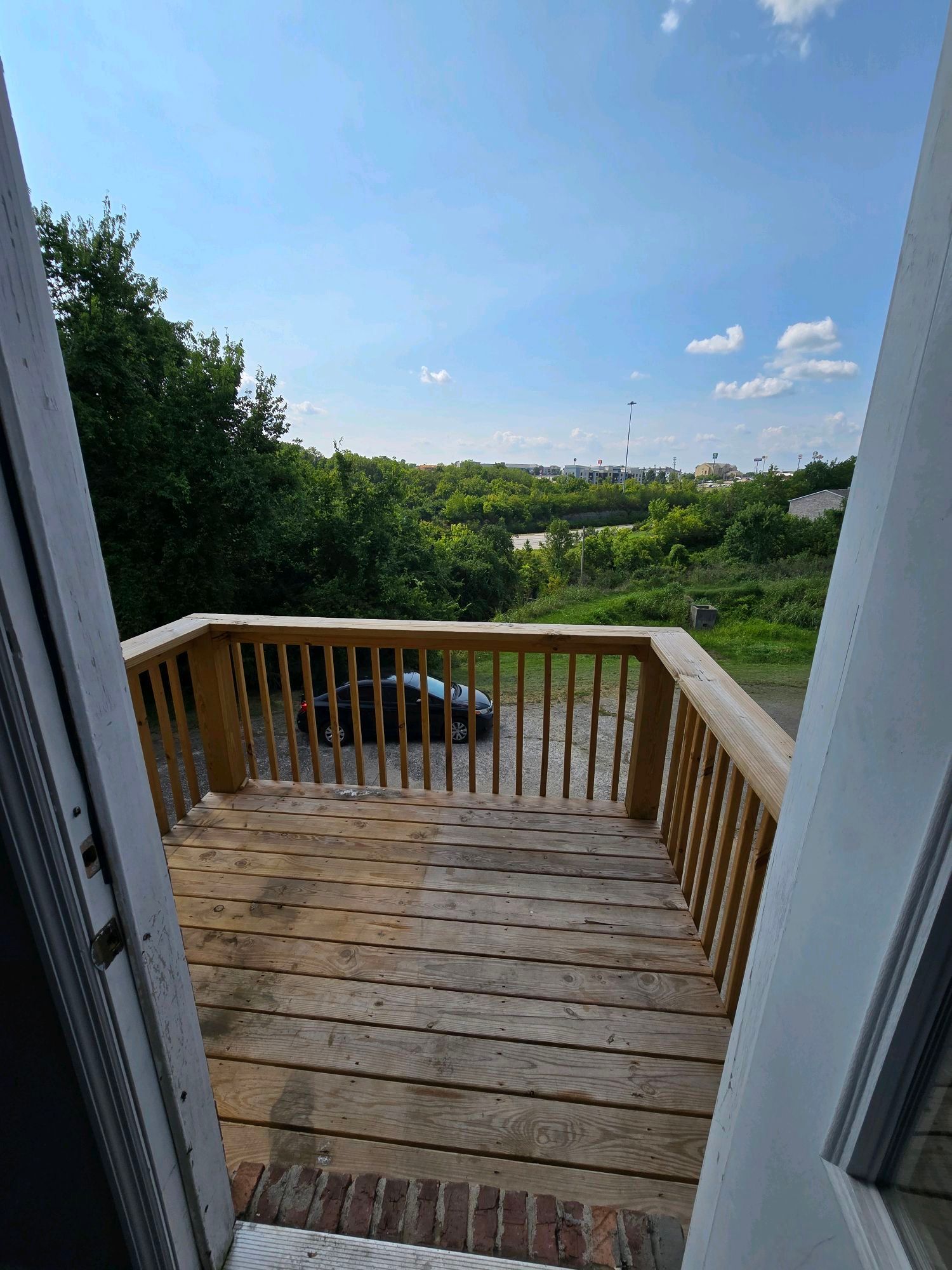 A wooden deck with a railing and a car parked on it.