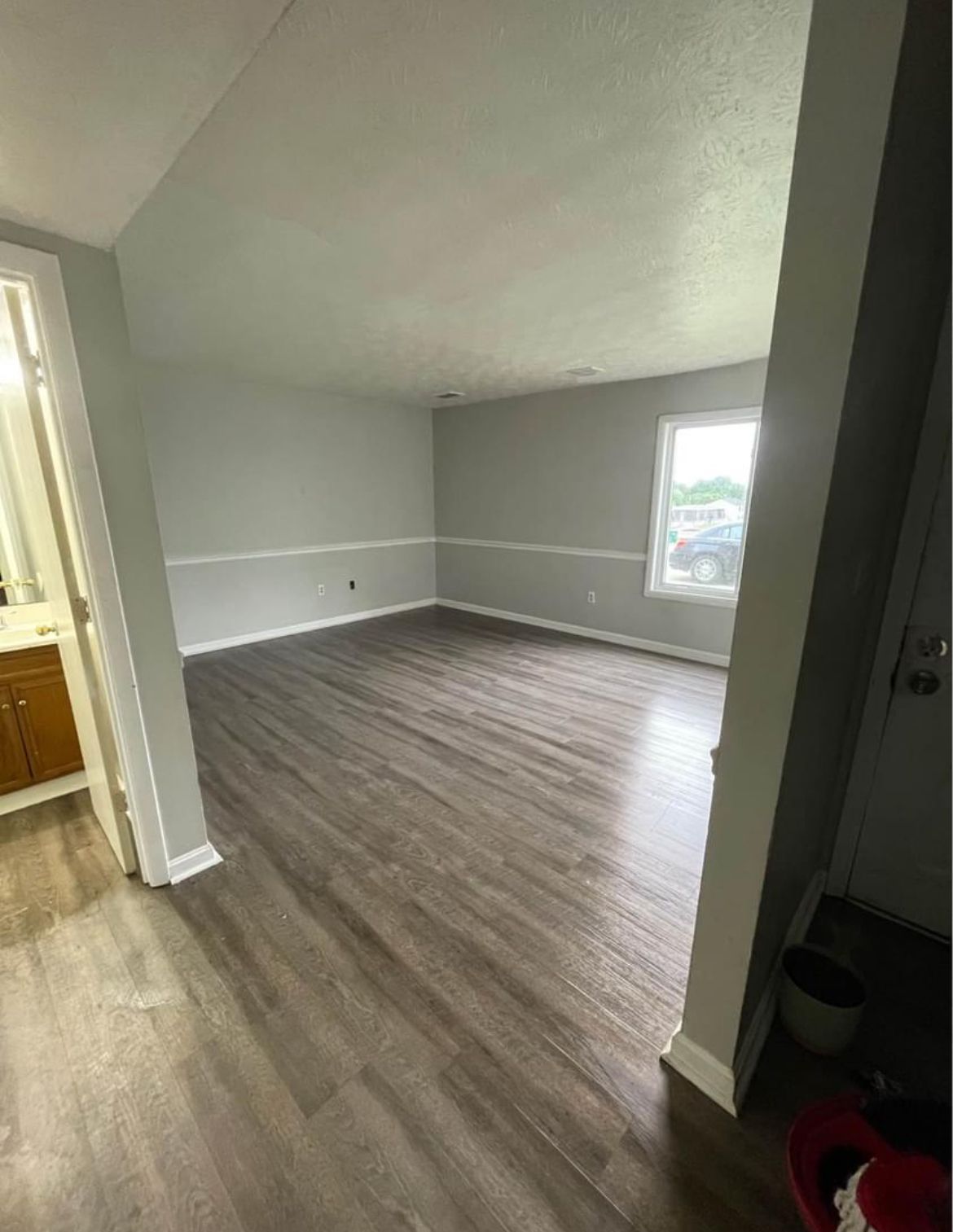 An empty living room with hardwood floors and a window.