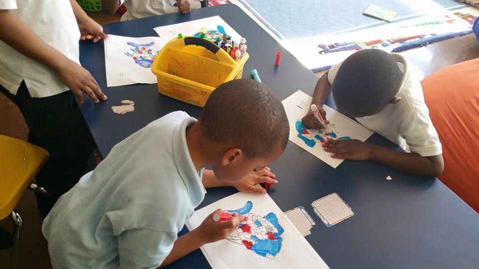 A group of children are sitting at a table drawing