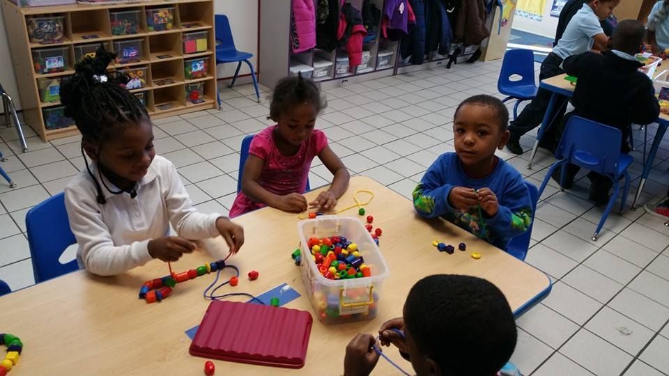 A group of children are sitting at a table playing with toys.