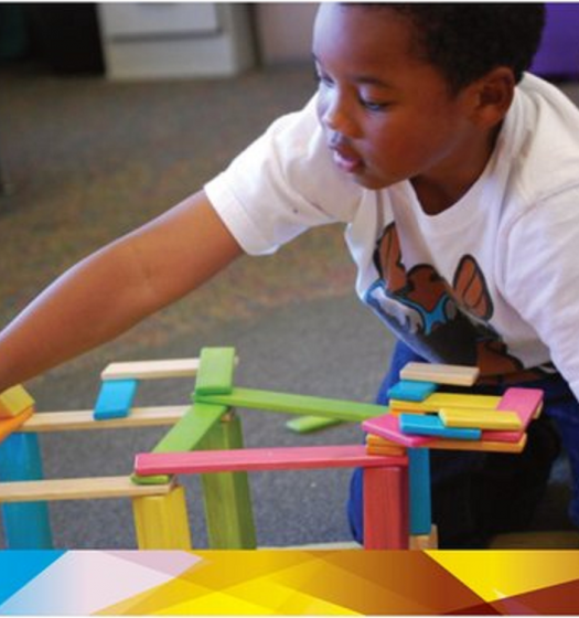 A young boy in a white shirt is playing with colorful wooden blocks