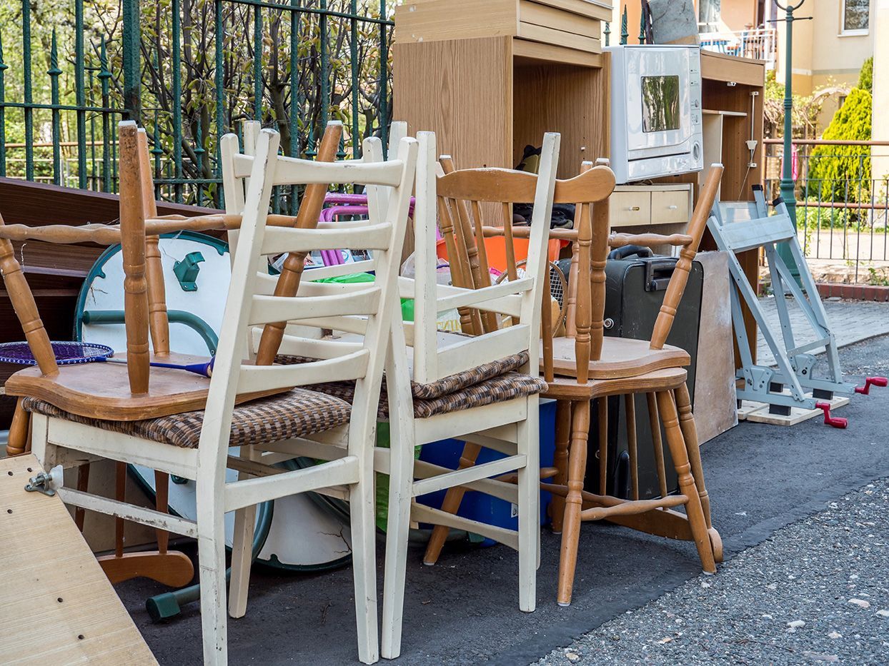 A bunch of chairs are stacked on top of each other on the side of the road.