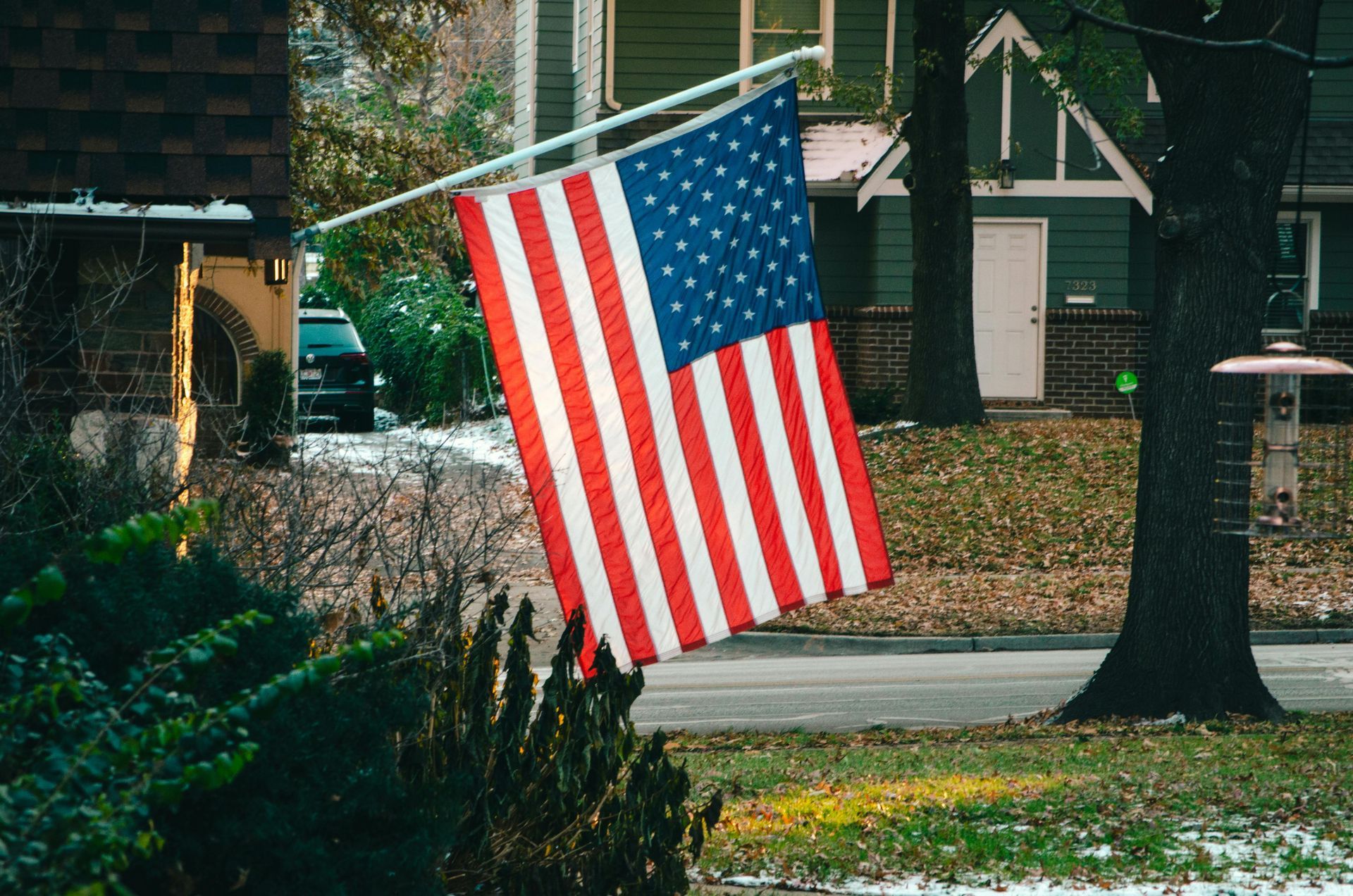 An American flag is flying in front of a house.