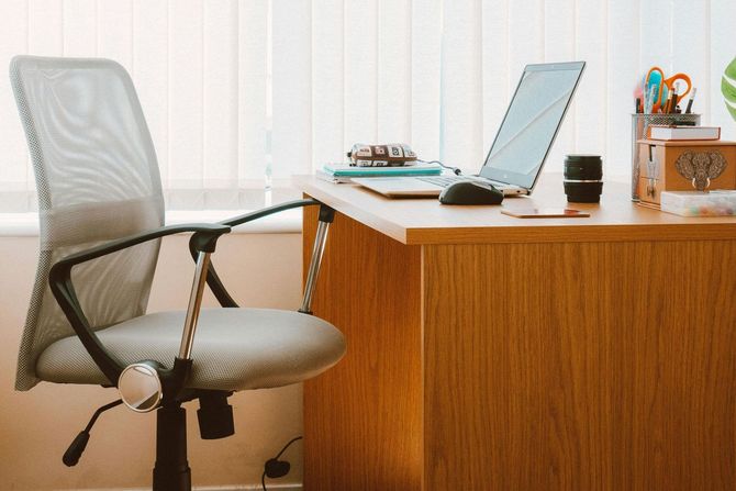 A desk with a chair and a laptop on it.