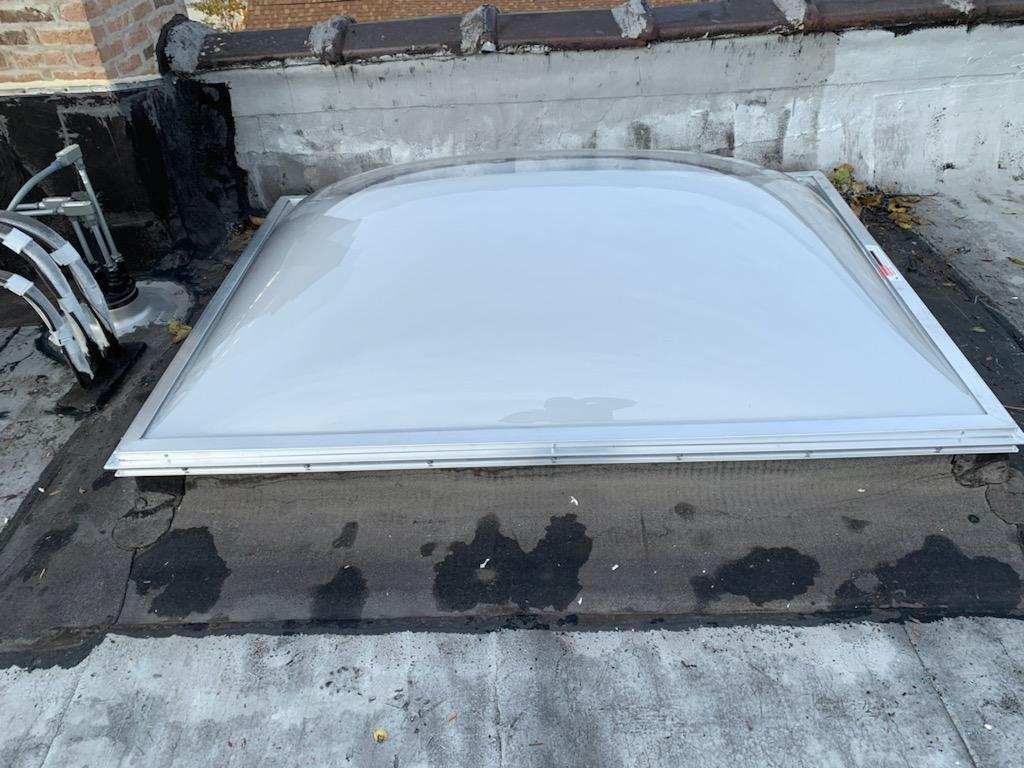 A white skylight is sitting on top of a roof.