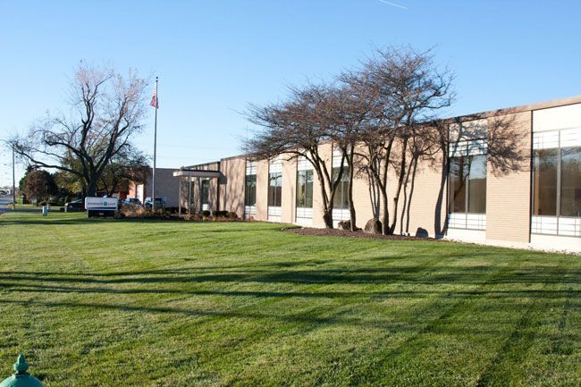 A Large Building with a Lush Green Lawn in Front of It.
