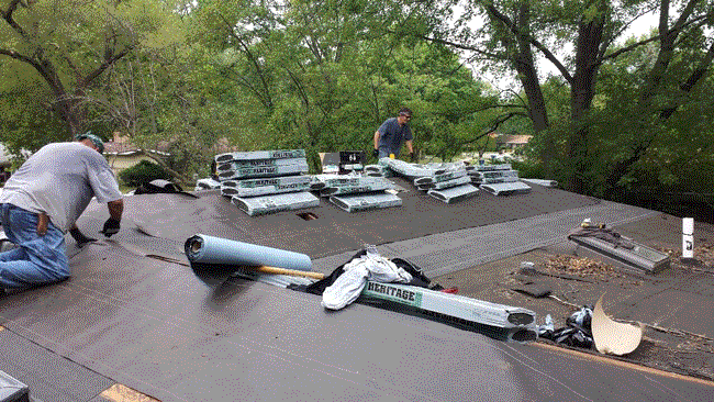 Two Repairmen Are on the Rooftop of a House, Fixing the Roof.
