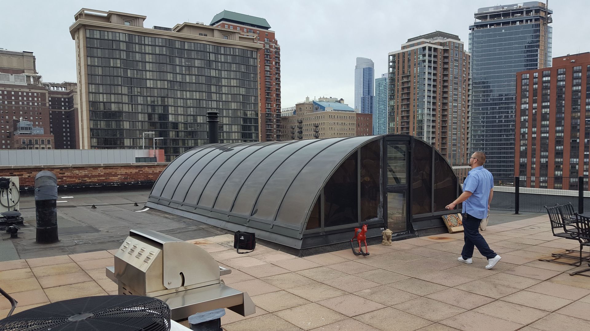 A man is walking on a rooftop with a large dome in the background.