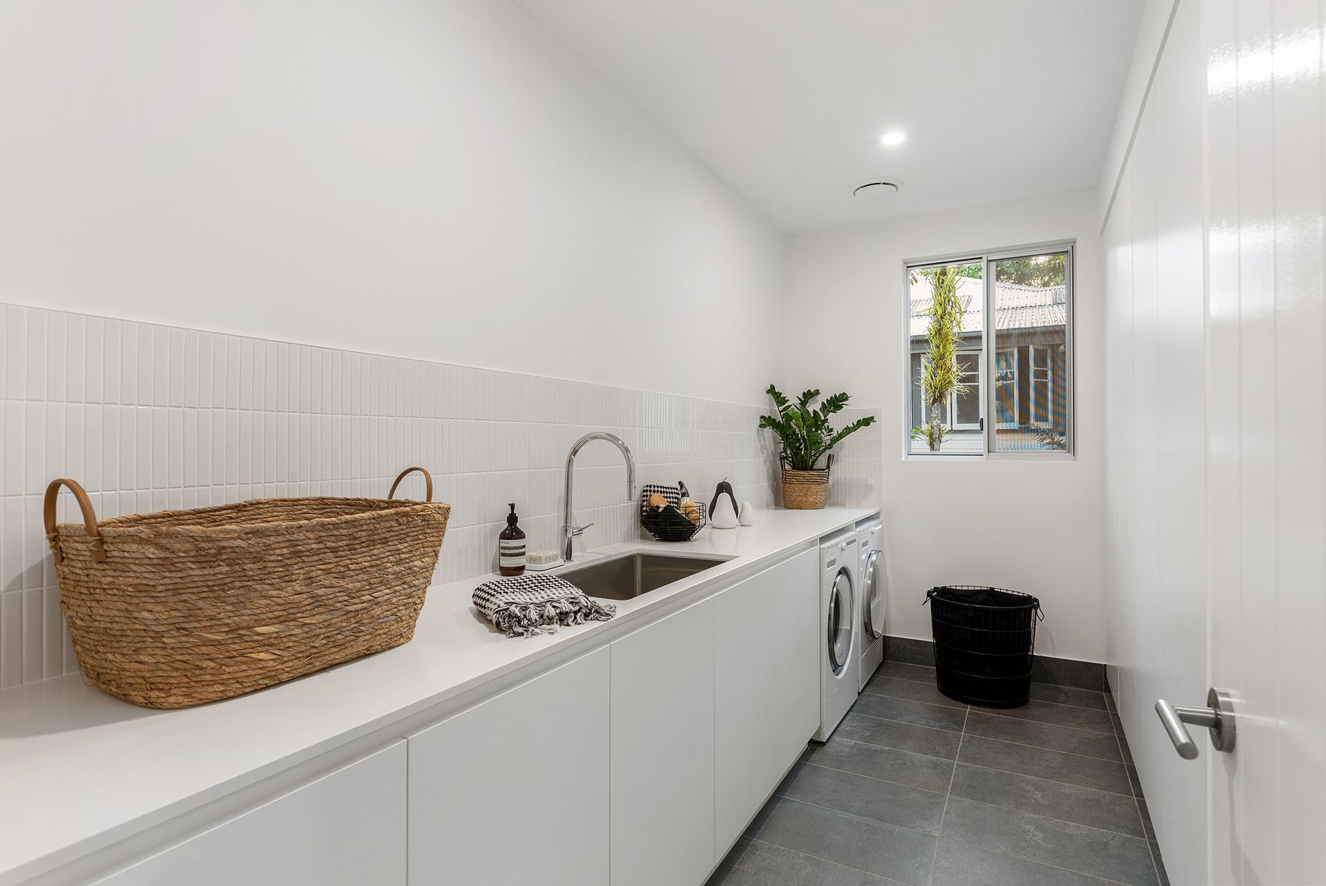 A laundry room with a sink , washer and dryer , and a window.