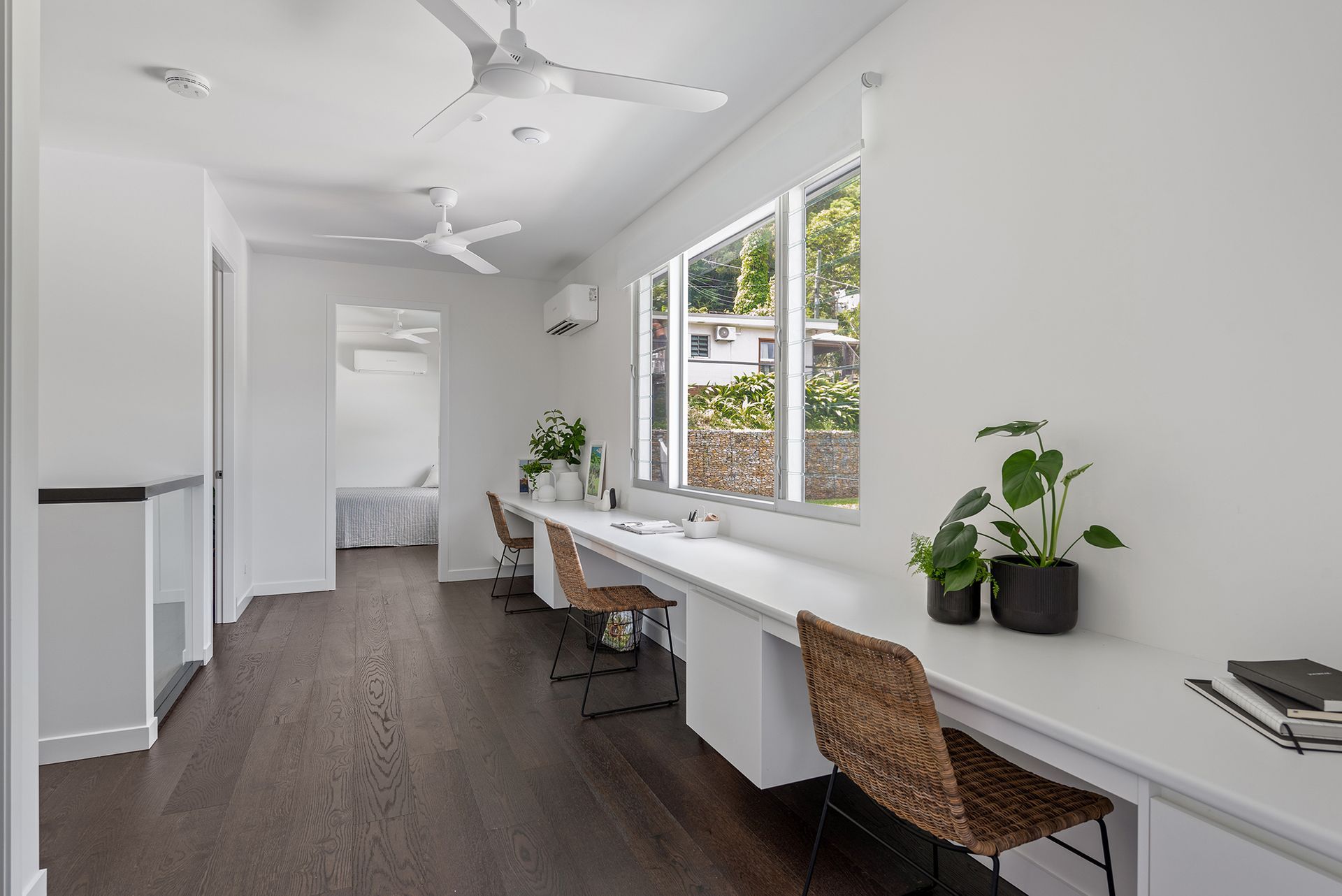 There is a long desk with two chairs in the middle of the room.