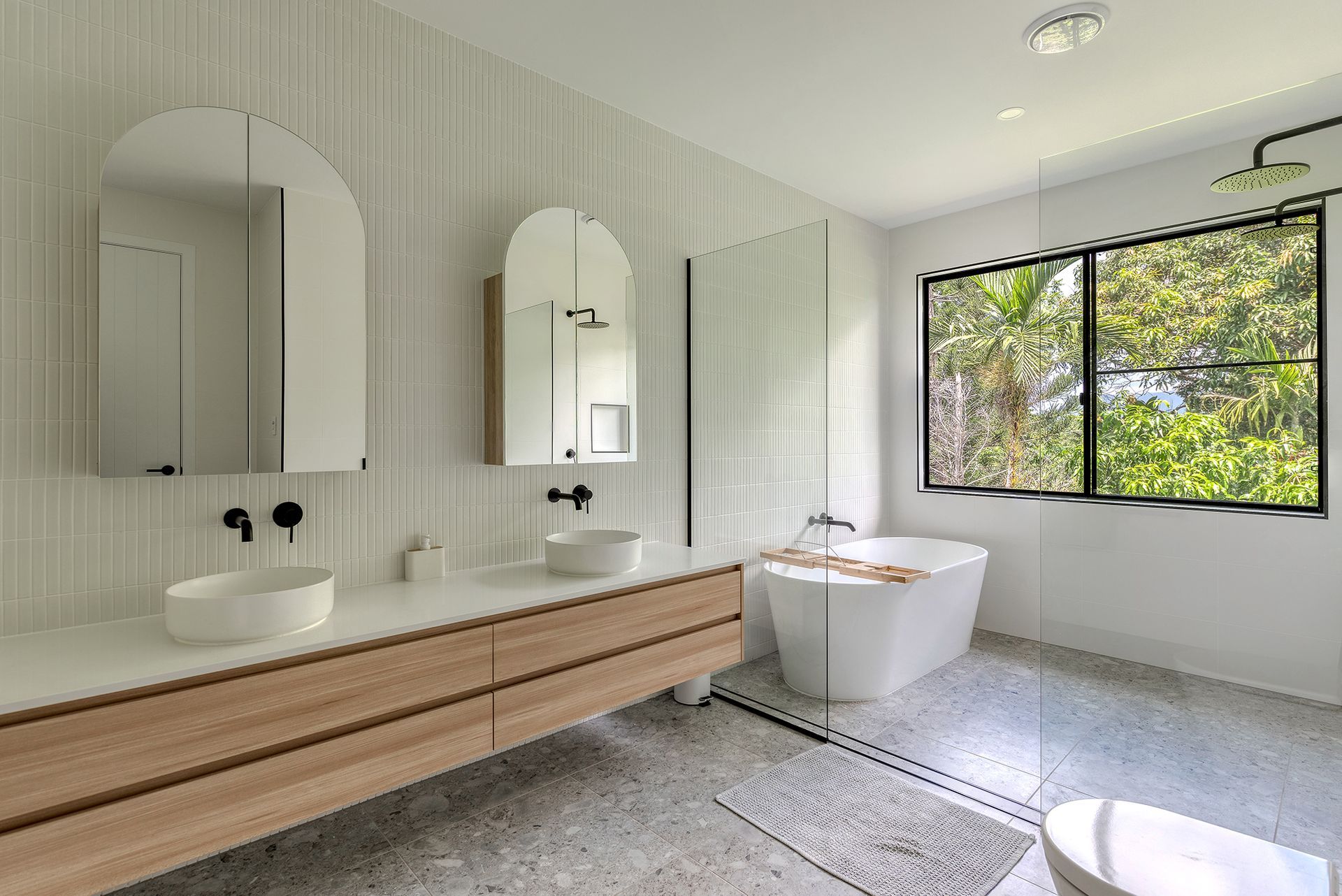 A bathroom with two sinks , a tub , and a window.