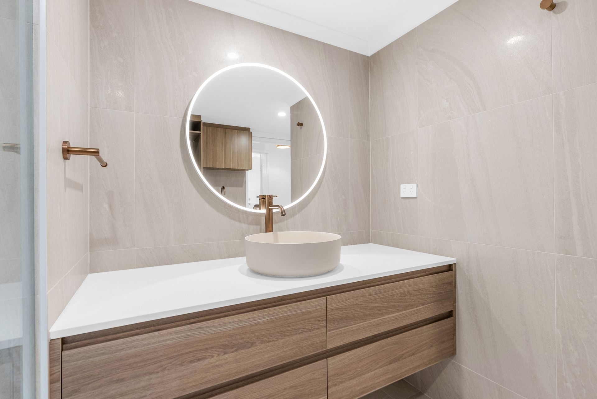 A bathroom with a sink and a round mirror.