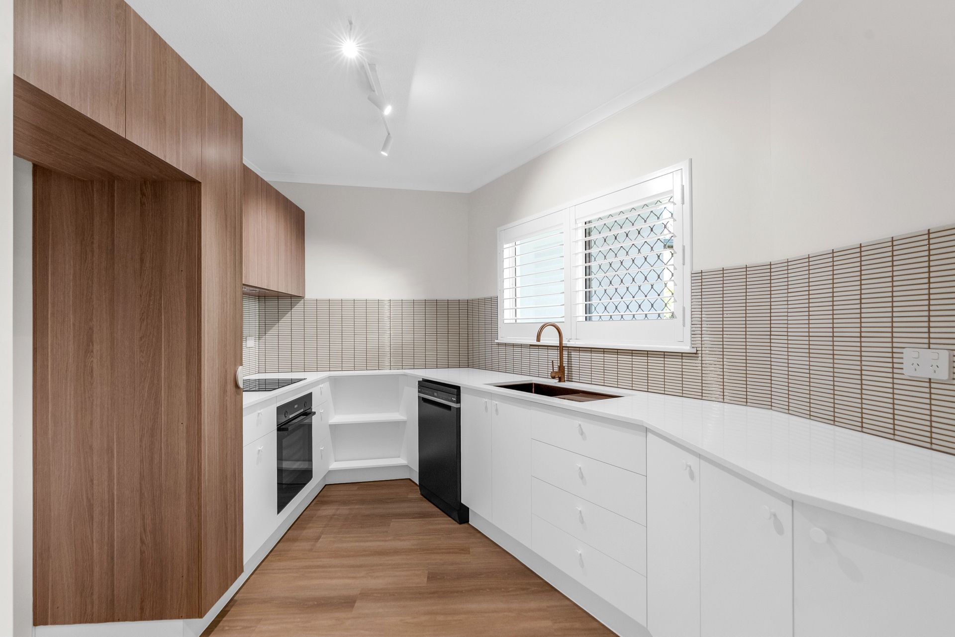 A kitchen with white cabinets and wooden floors and a sink.