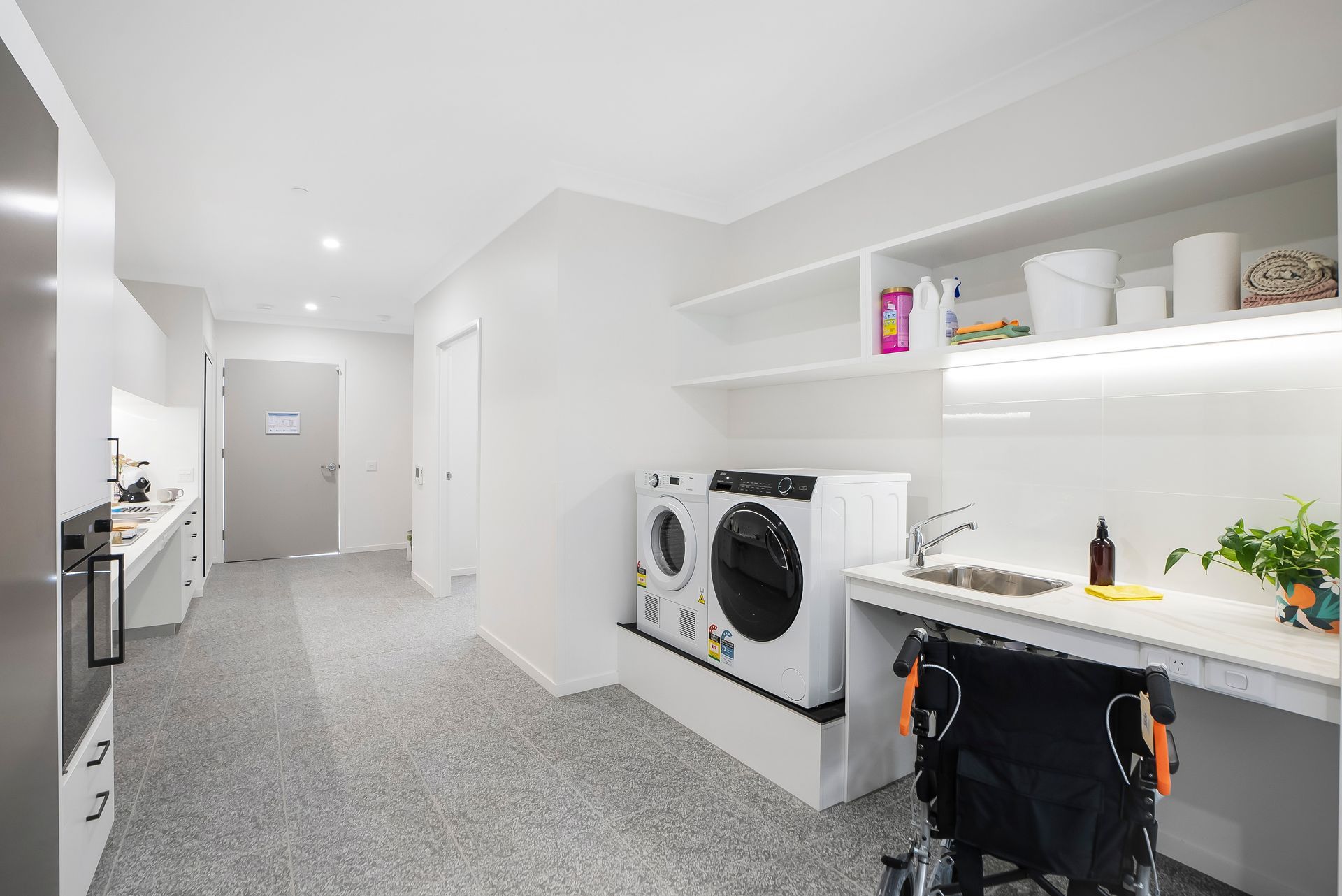 A laundry room with a washer and dryer and a wheelchair.