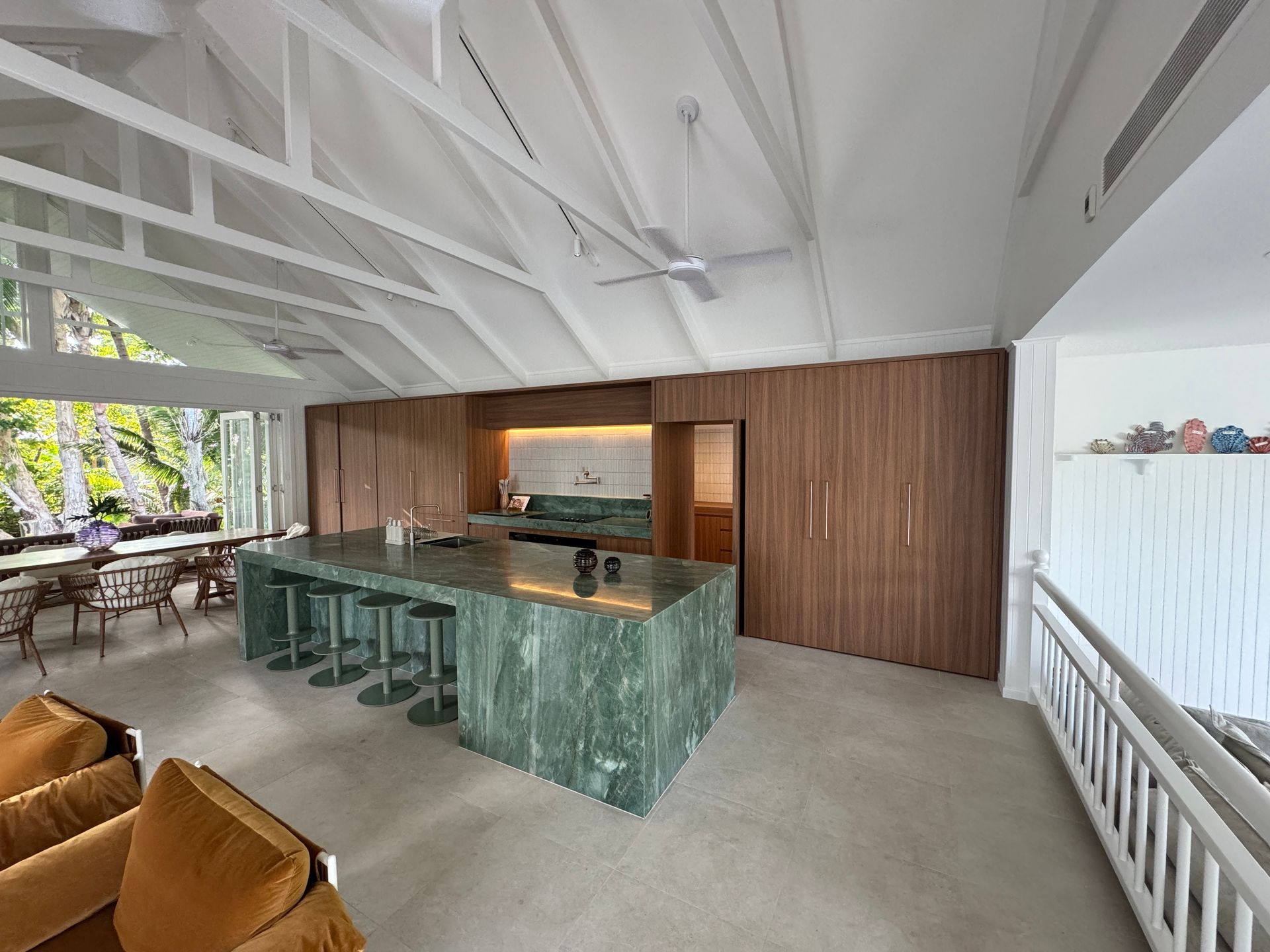 A large kitchen with a green island and a ceiling fan.