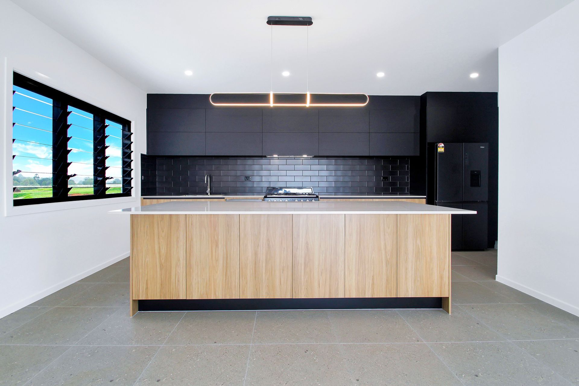 An empty kitchen with black cabinets and a large island
