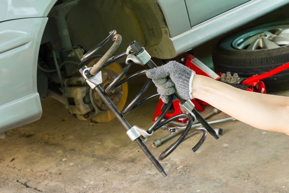 A Person is Holding a Pair of Pliers in Front of a Car — Mick Dunn Motor Repairs in Mackay, QLD