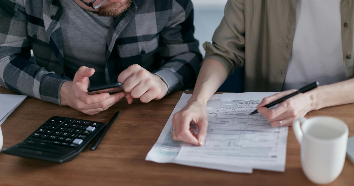 Individuals reviewing probate documents and discussing estate planning, with a calculator and paperwork on a table, reflecting the complexities of navigating probate without a will.