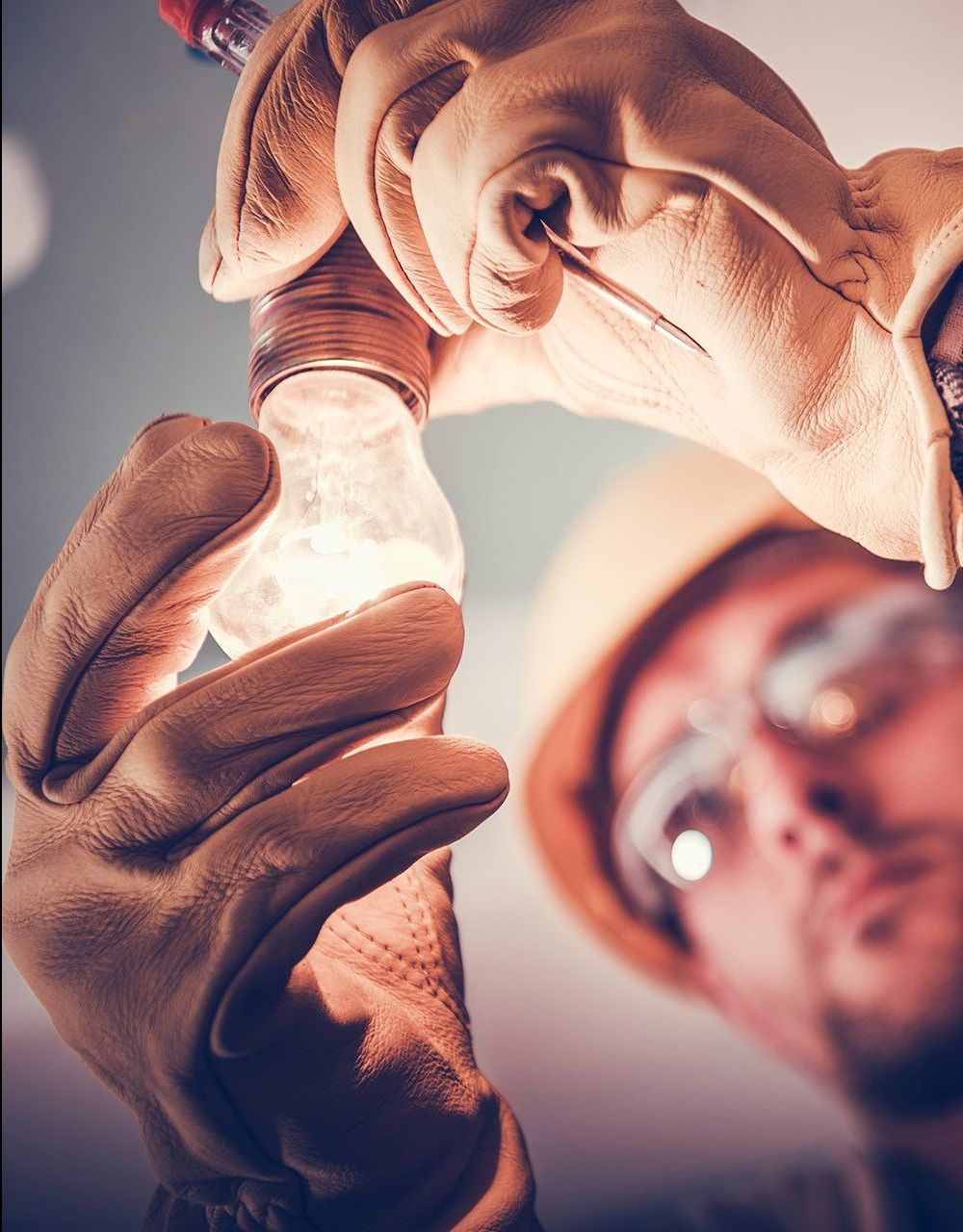 A man wearing gloves is holding a light bulb