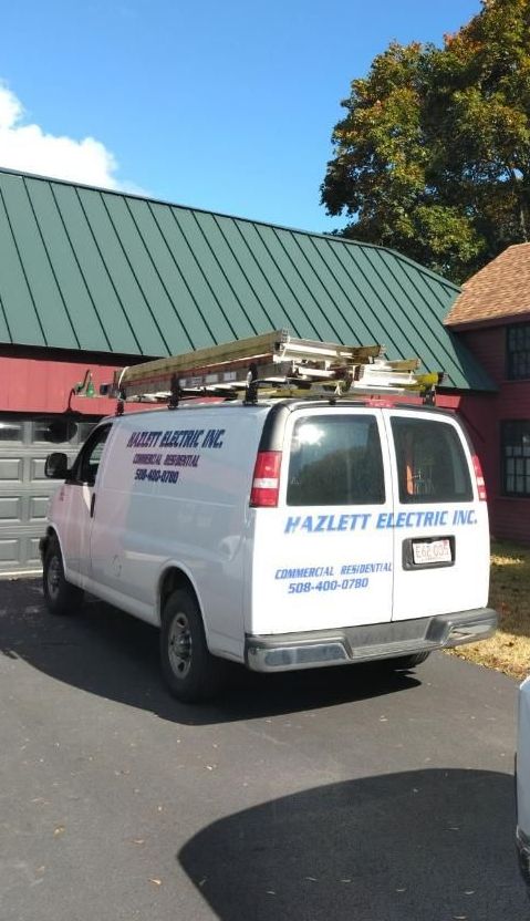 A white van is parked in front of a building with a green roof.